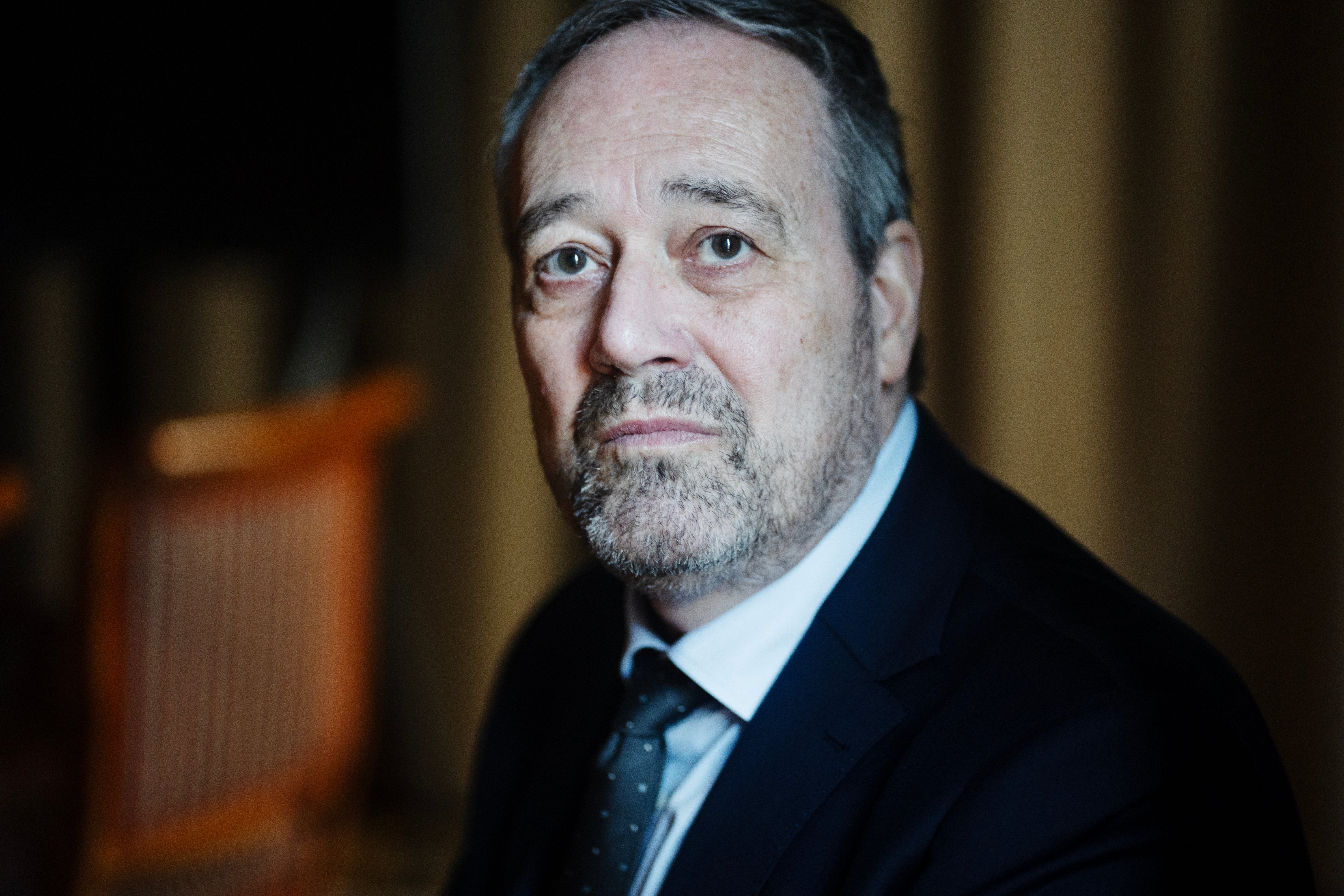 Porträttfoto av en man i kostym och slips mot en suddig bakgrund.