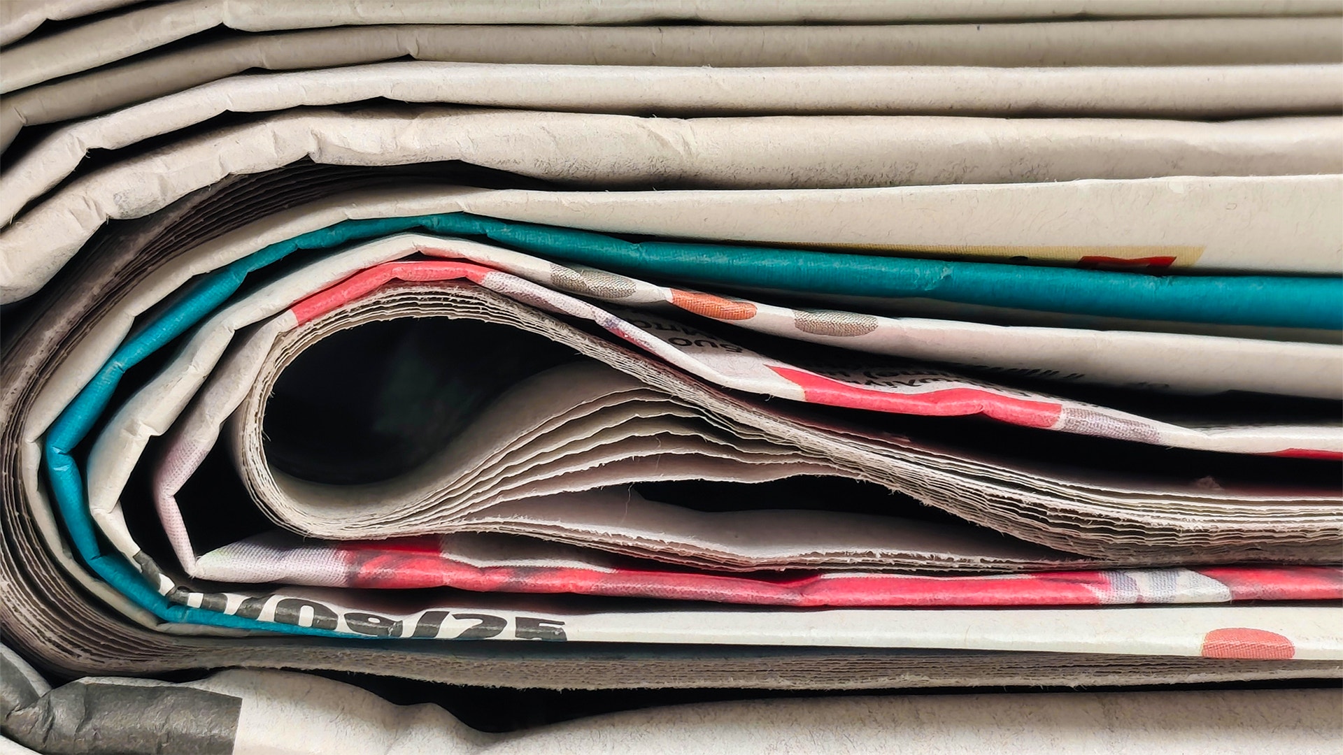 Stapel av tidningar och tidskrifter liggande på varandra, visar de färgglada omslagens kanter.