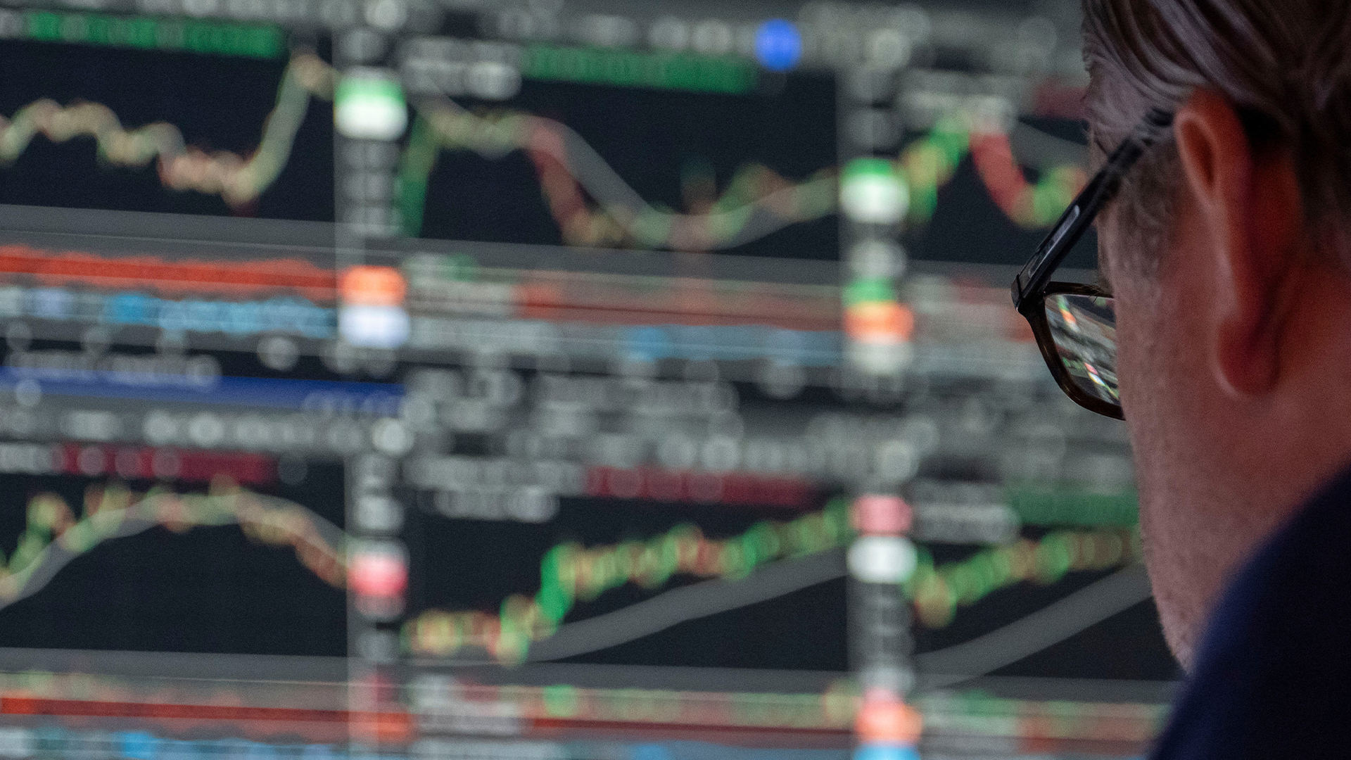 En person betraktar skärmar med börskurvor och finansiell data.