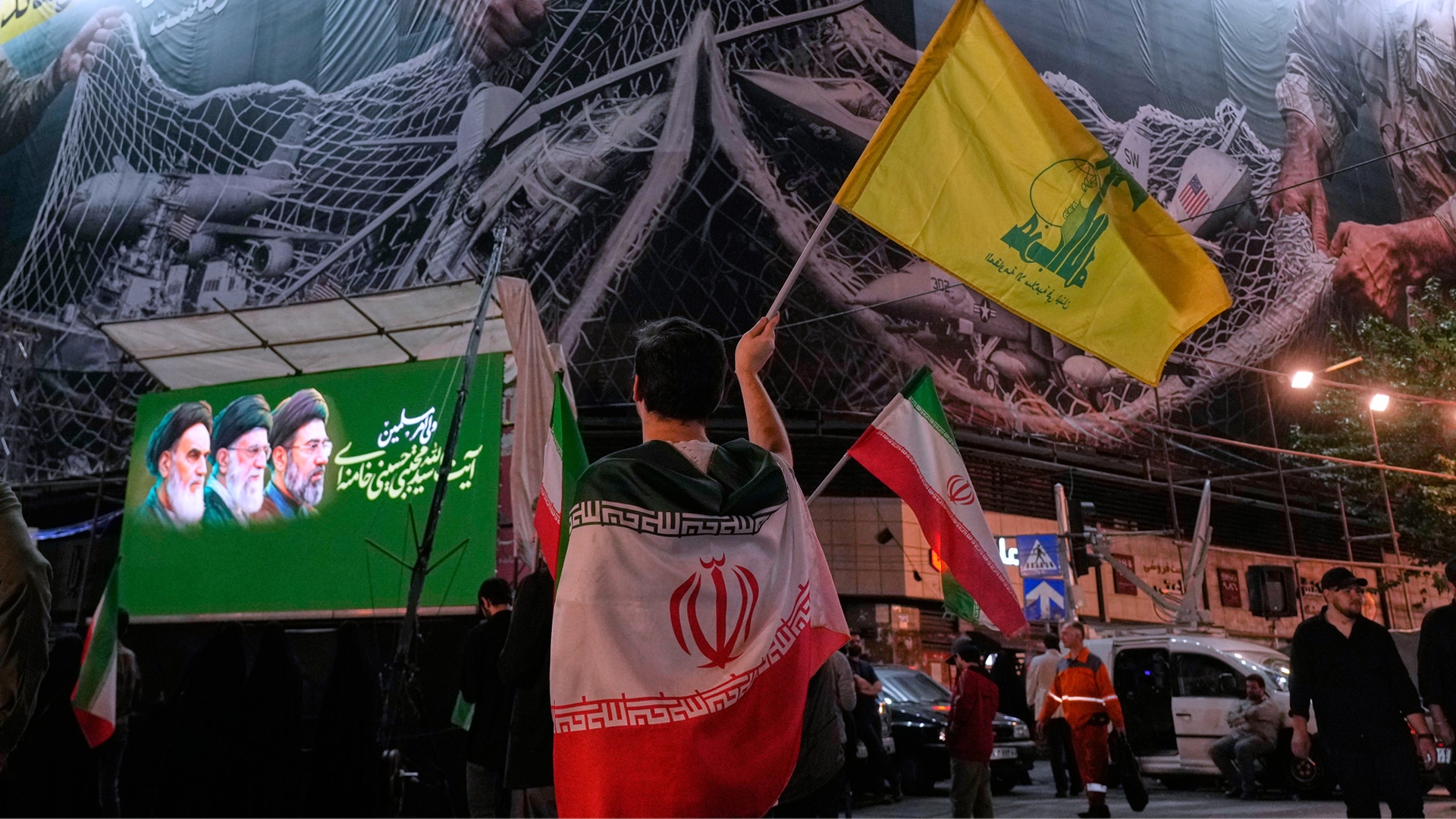 Gatuscen med iranska flaggor och banderoller med religiösa och politiska symboler upphängda på en byggnad.