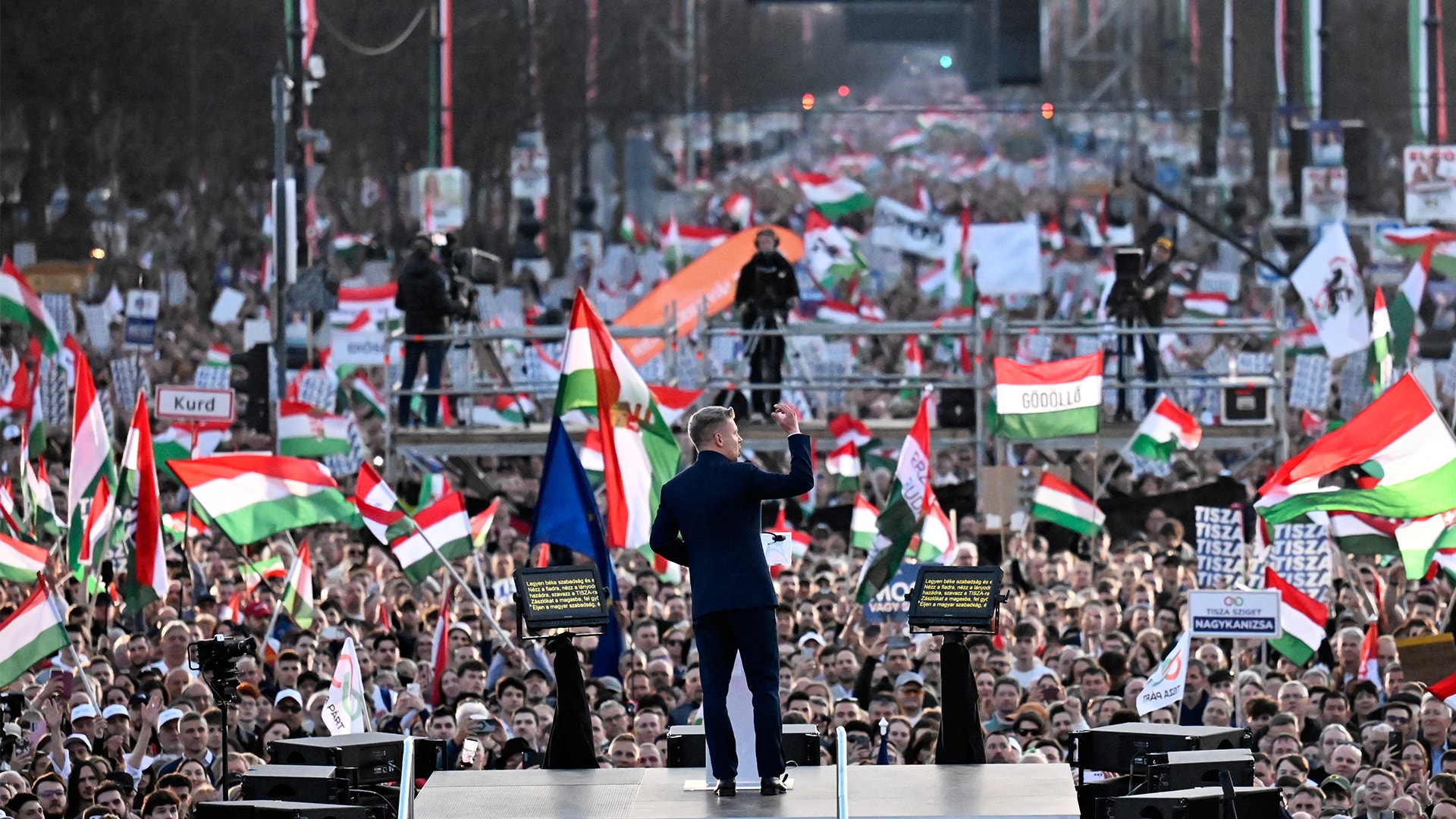 En stor folksamling med människor som håller upp ungerska flaggor under ett offentligt evenemang.