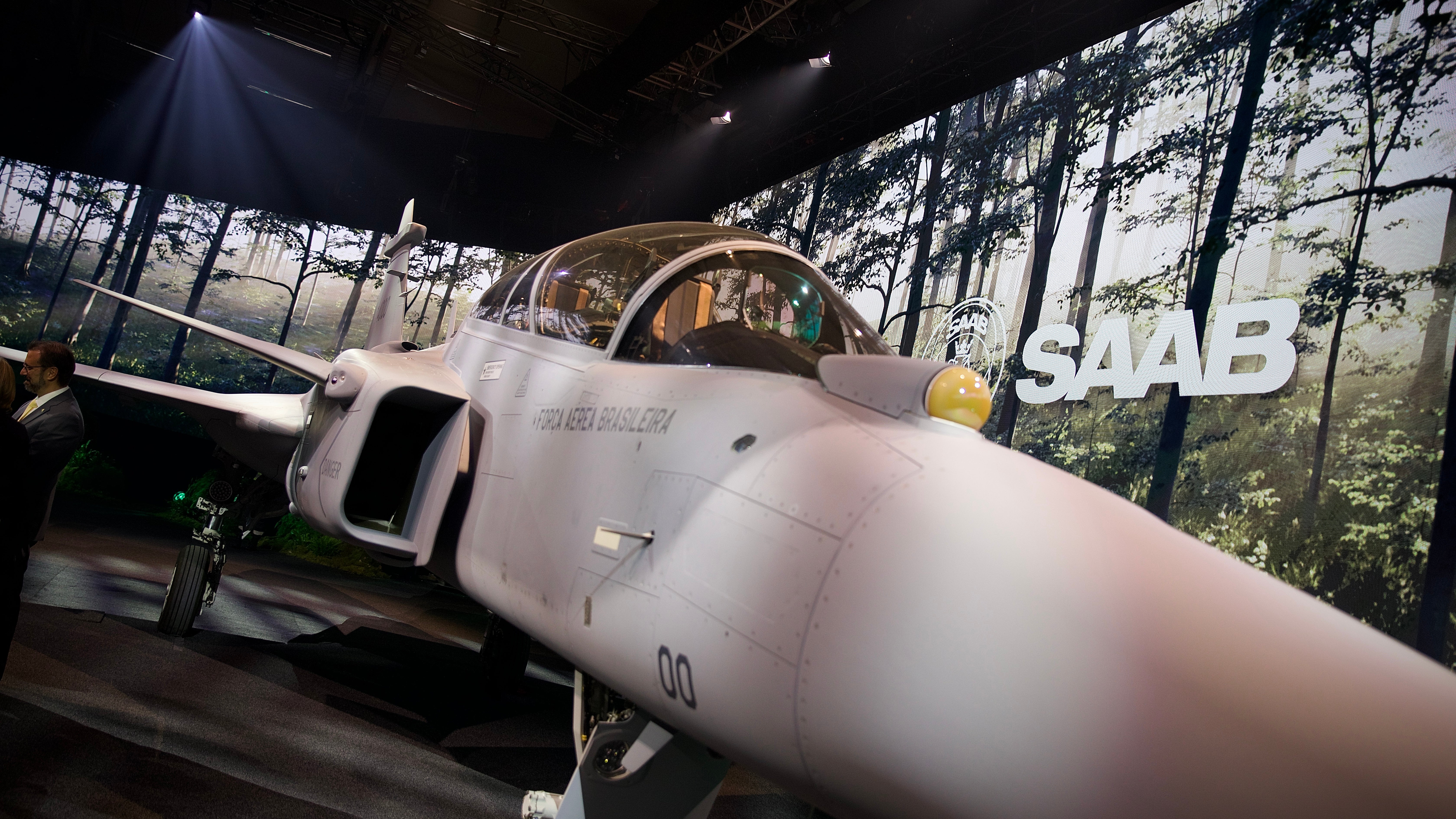 Ett klassiskt vitt SAAB-stridsflygplan från 1950-talet på utställning i ett museum, belyst av spotlights.