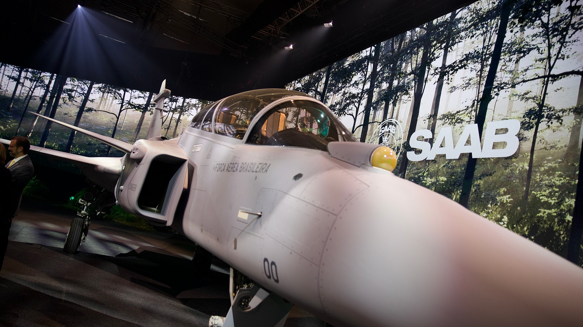 Ett klassiskt vitt SAAB-stridsflygplan från 1950-talet på utställning i ett museum, belyst av spotlights.