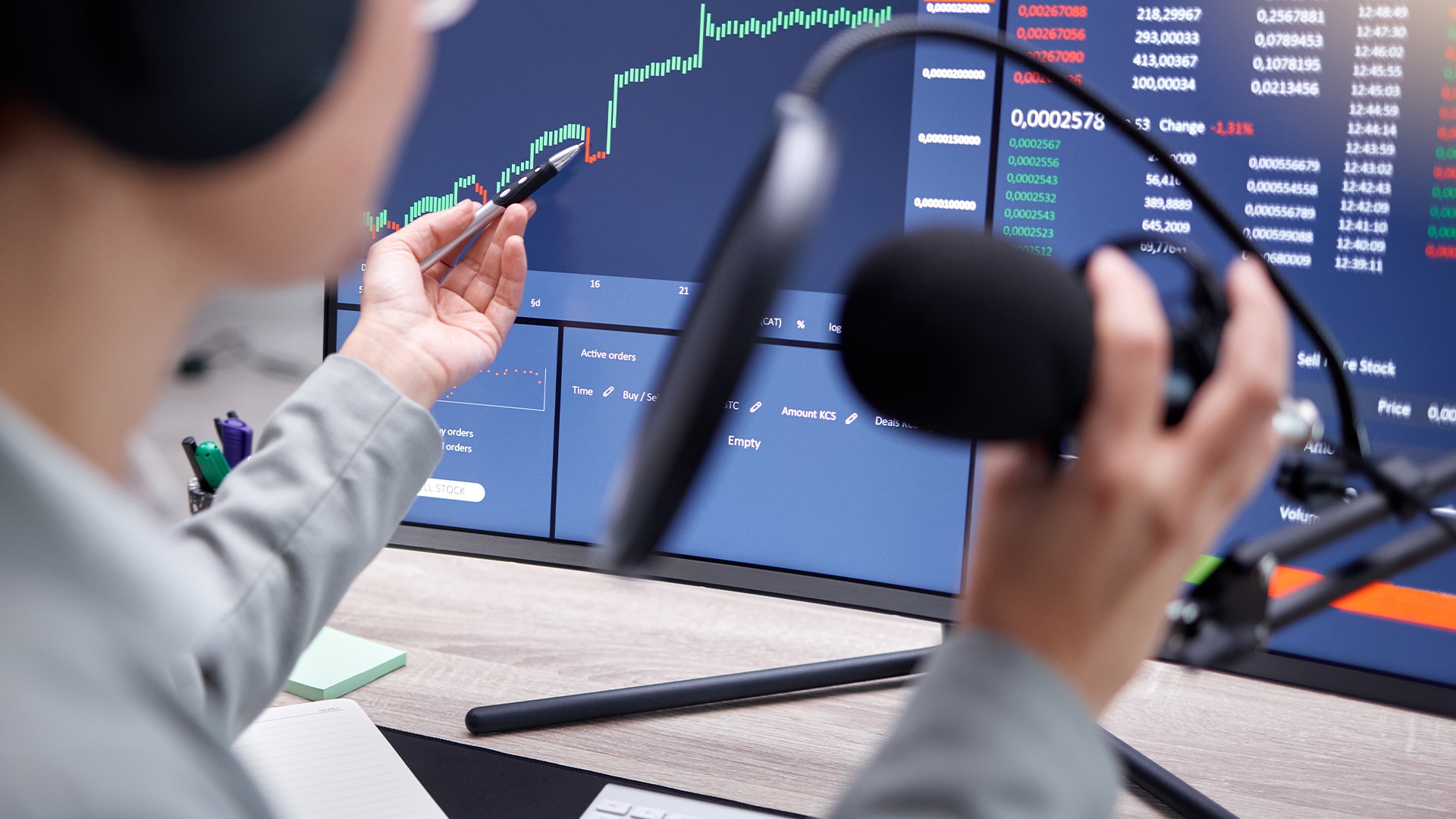 Person pekar på en datorskärm med finansiella grafer och marknadsdata medan den håller en datormus.