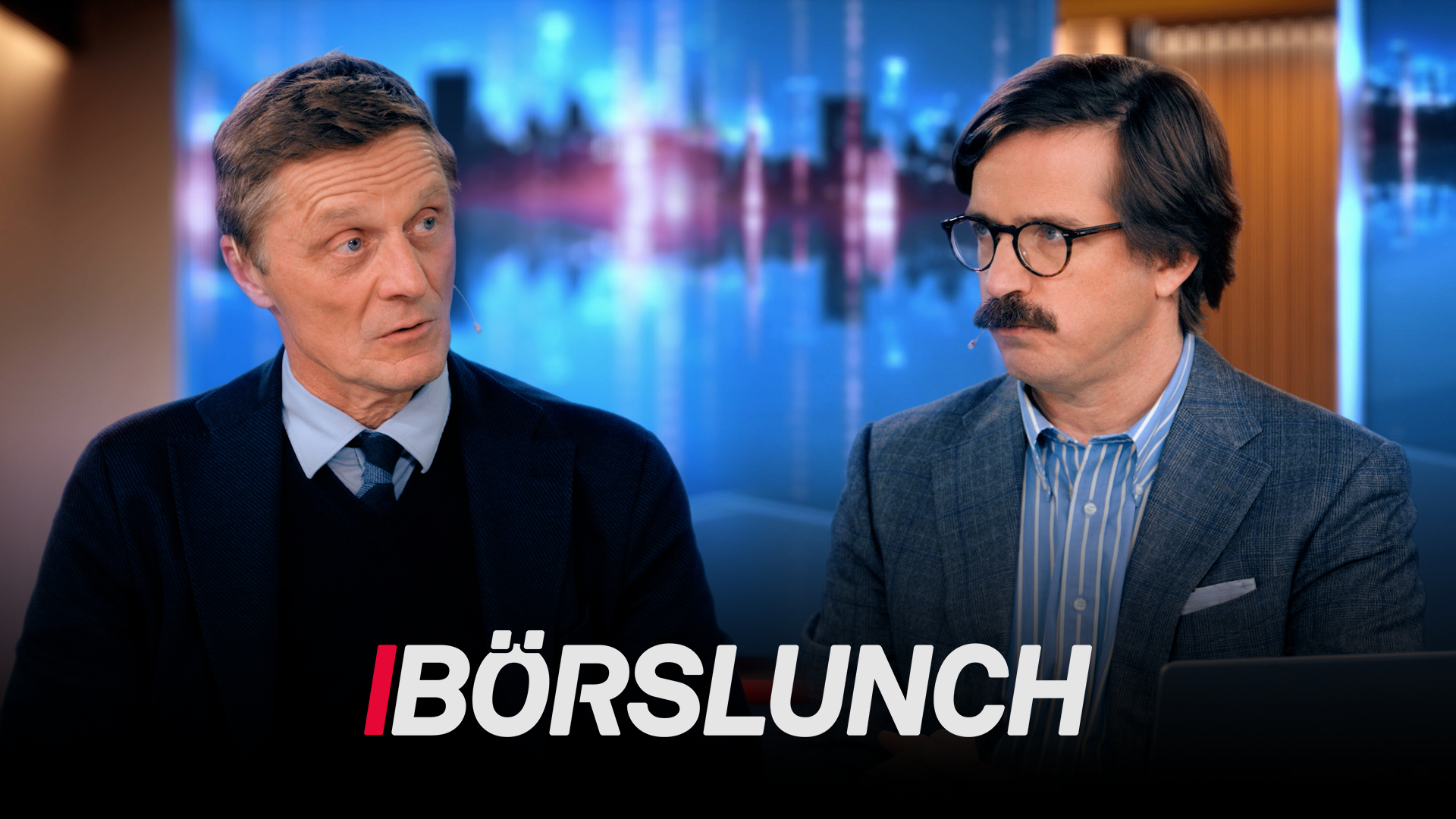 Två män i kavajer sitter i en tv-studio med en blå, suddig stadsbakgrund. Under dem syns programloggan Börslunch.