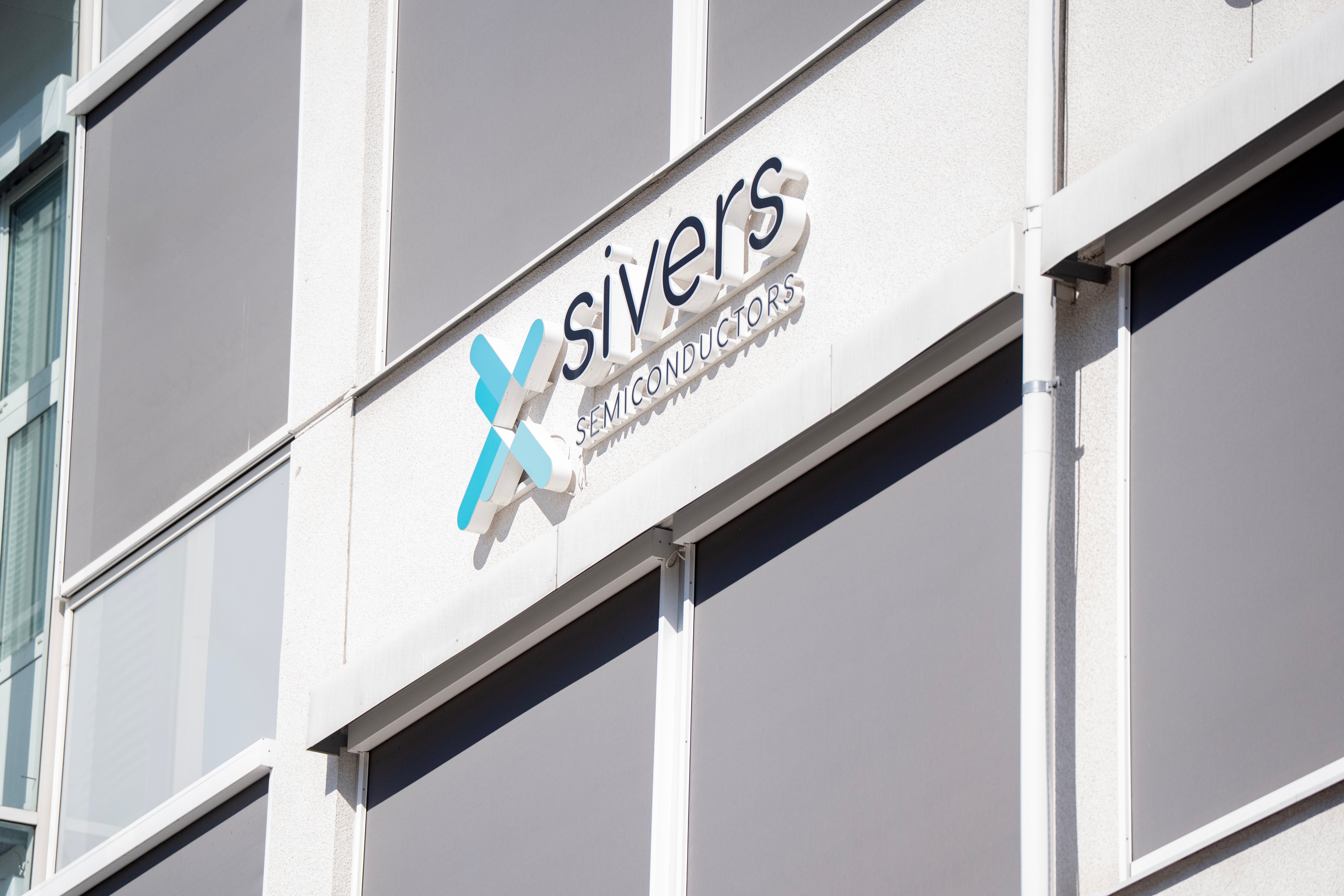 Sivers logotyp på en byggnadsfasad med vita och grå paneler.