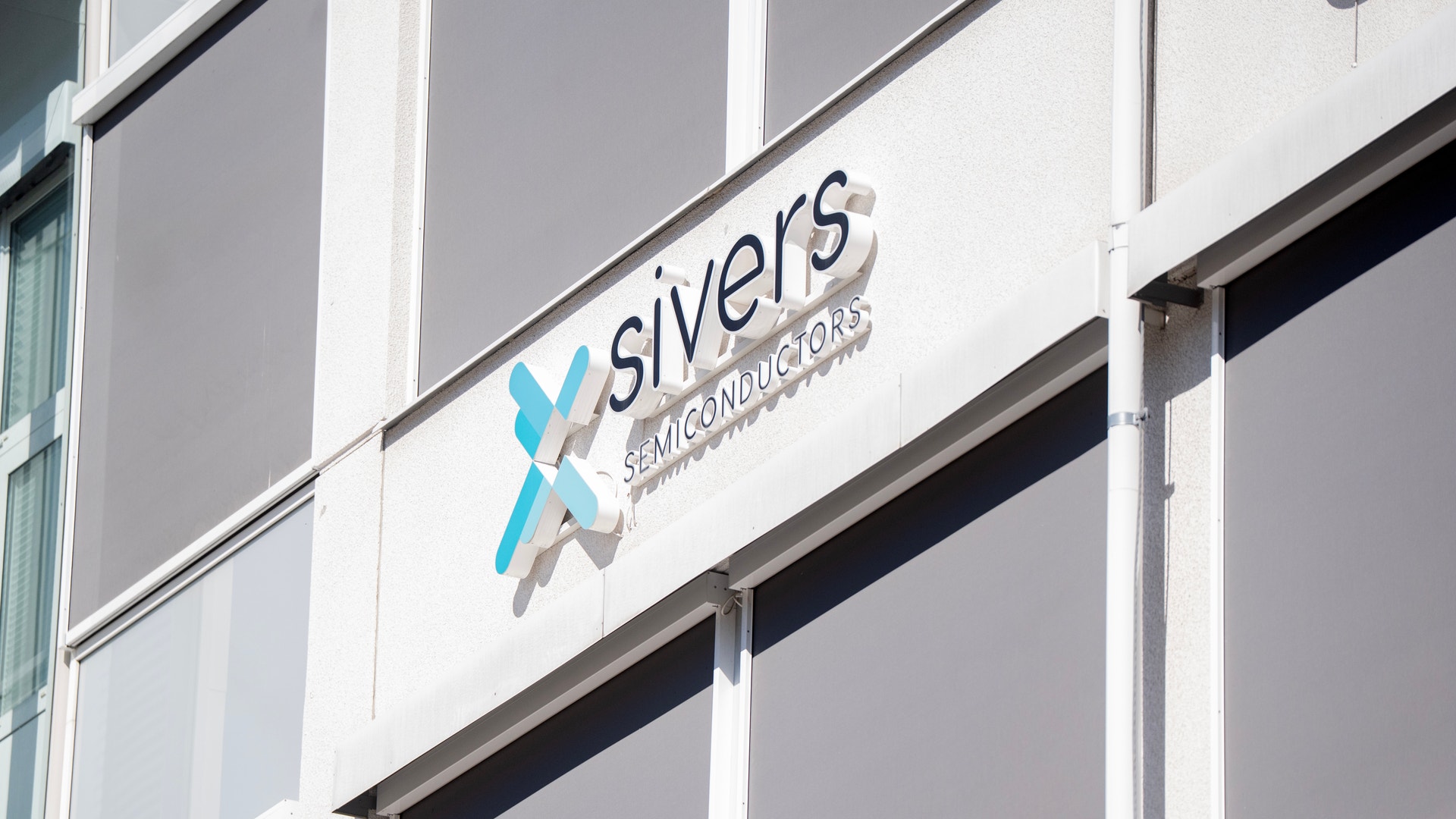 Sivers logotyp på en byggnadsfasad med vita och grå paneler.