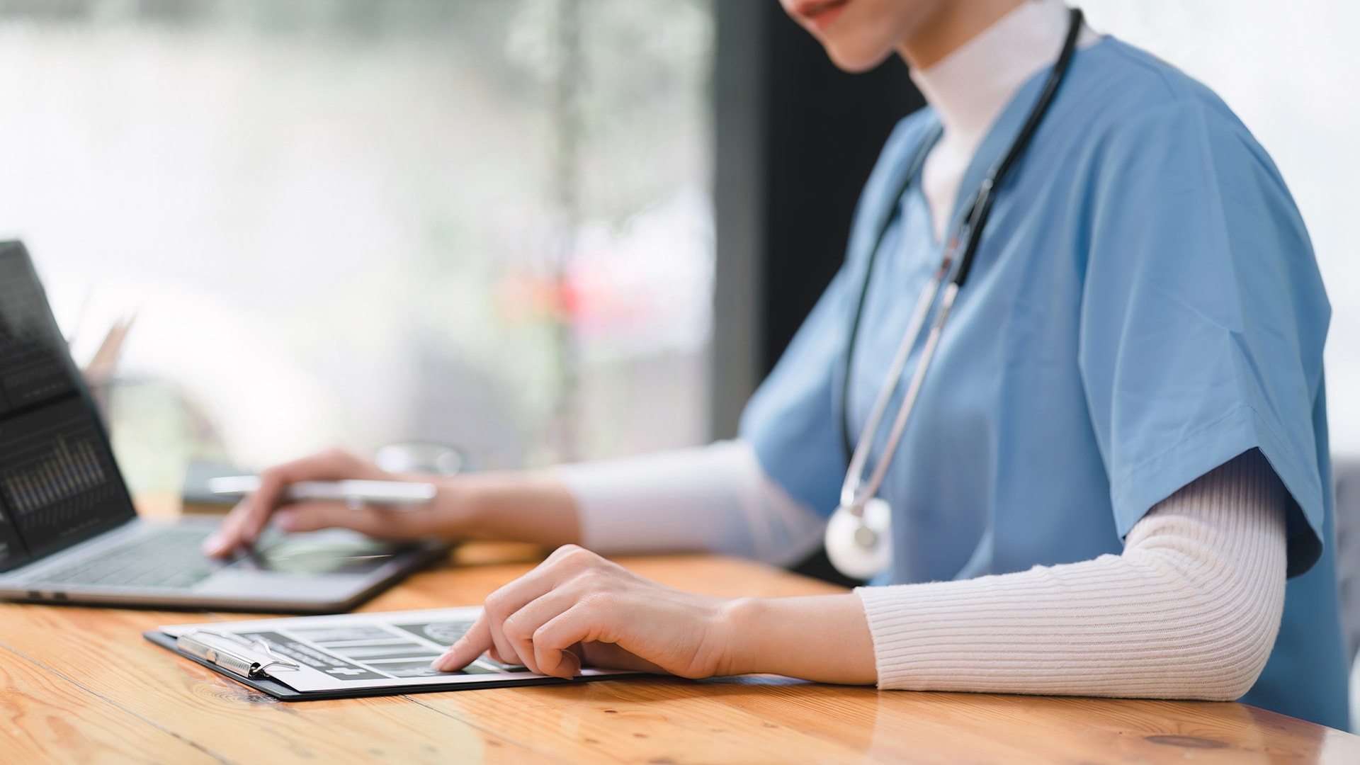 Sjuksköterska arbetar vid skrivbord med dator och papper