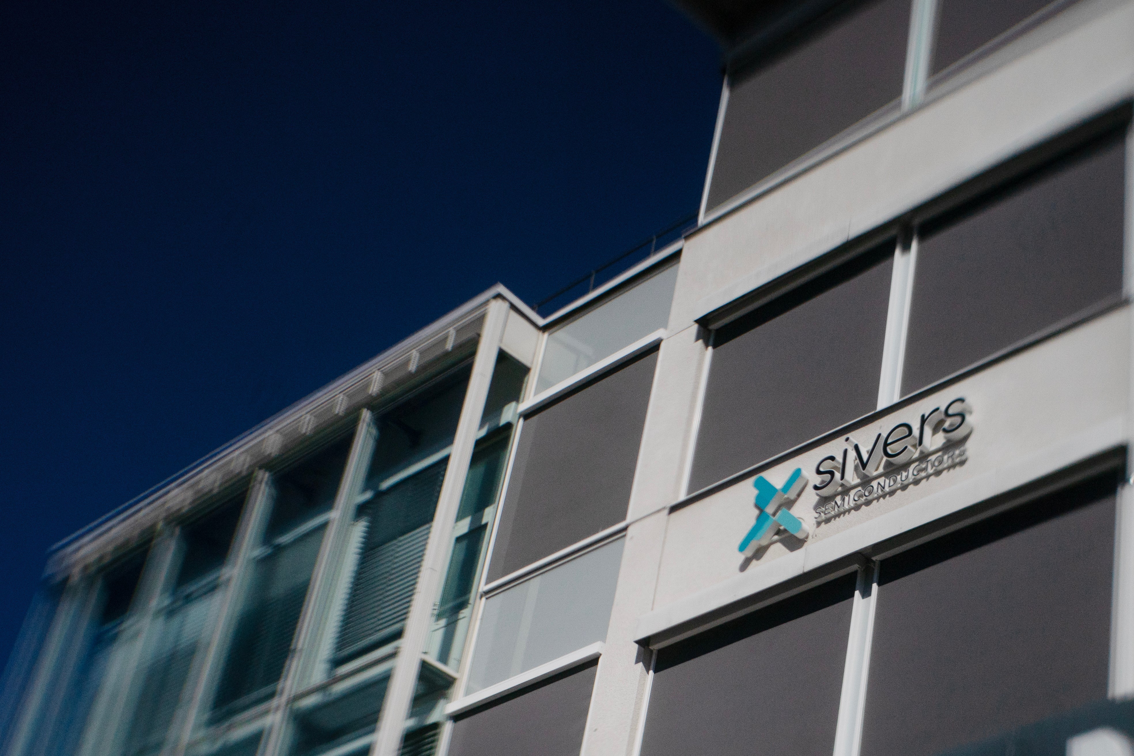 Modernt byggnadsfasad med Sivers-logotyp på vita paneler mot blå himmel
