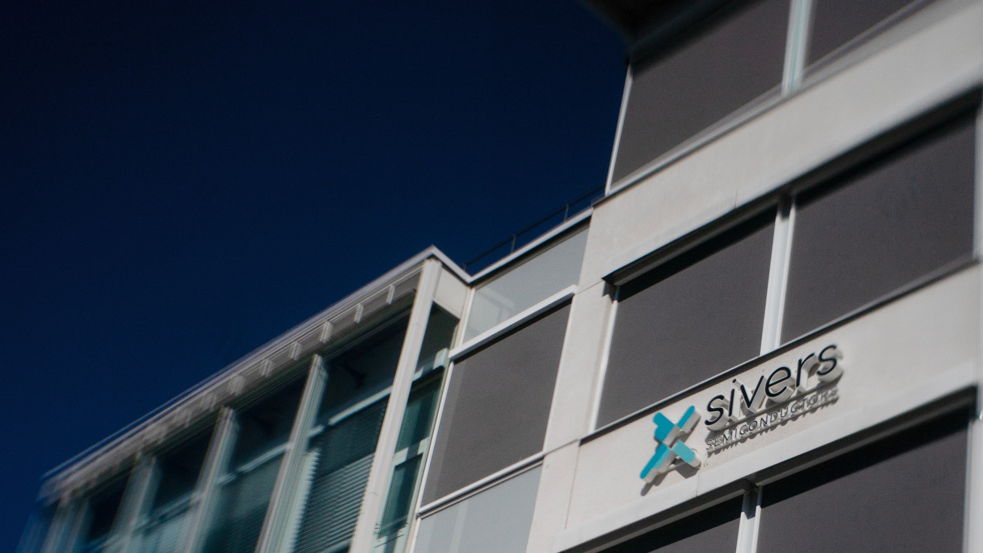 Modernt byggnadsfasad med Sivers-logotyp på vita paneler mot blå himmel