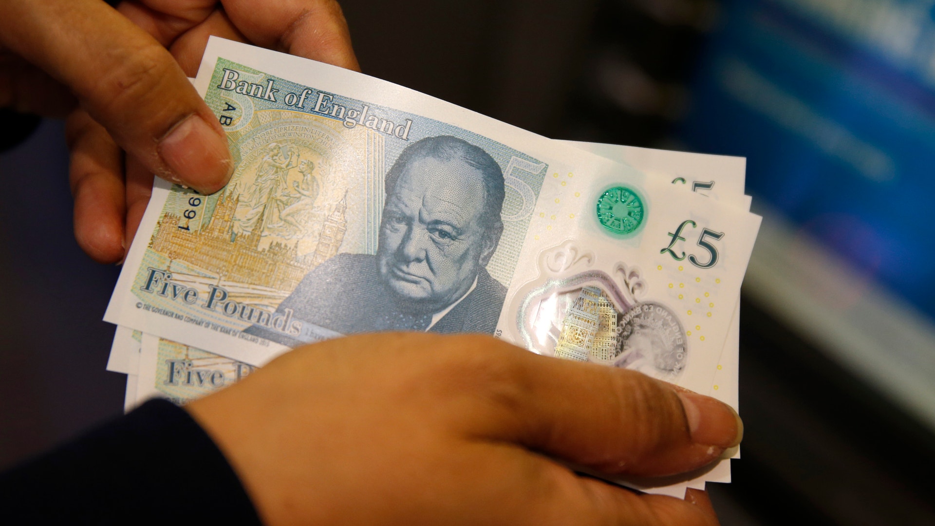 Händer som håller brittiska fempondersedlar