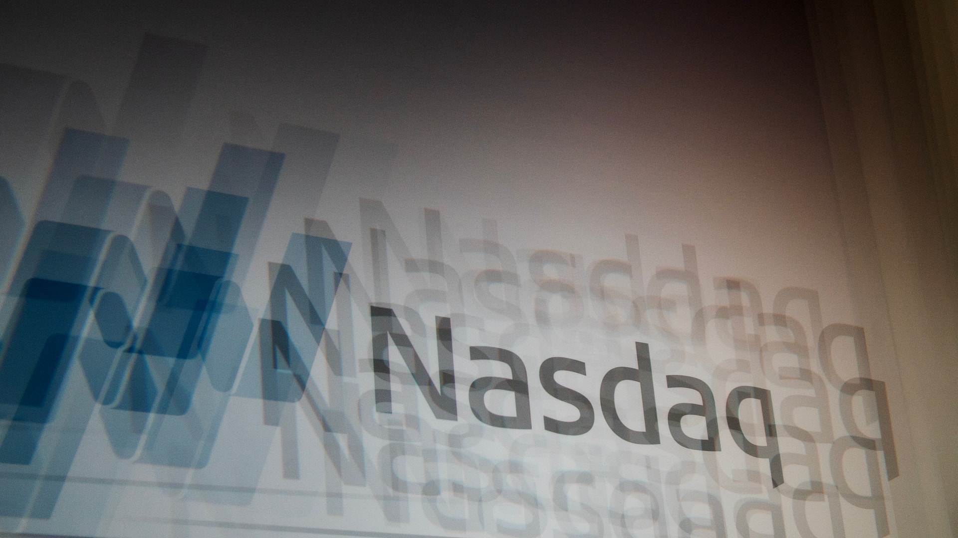 Nasdaq-logotyp med blå och vita geometriska former i bakgrunden.