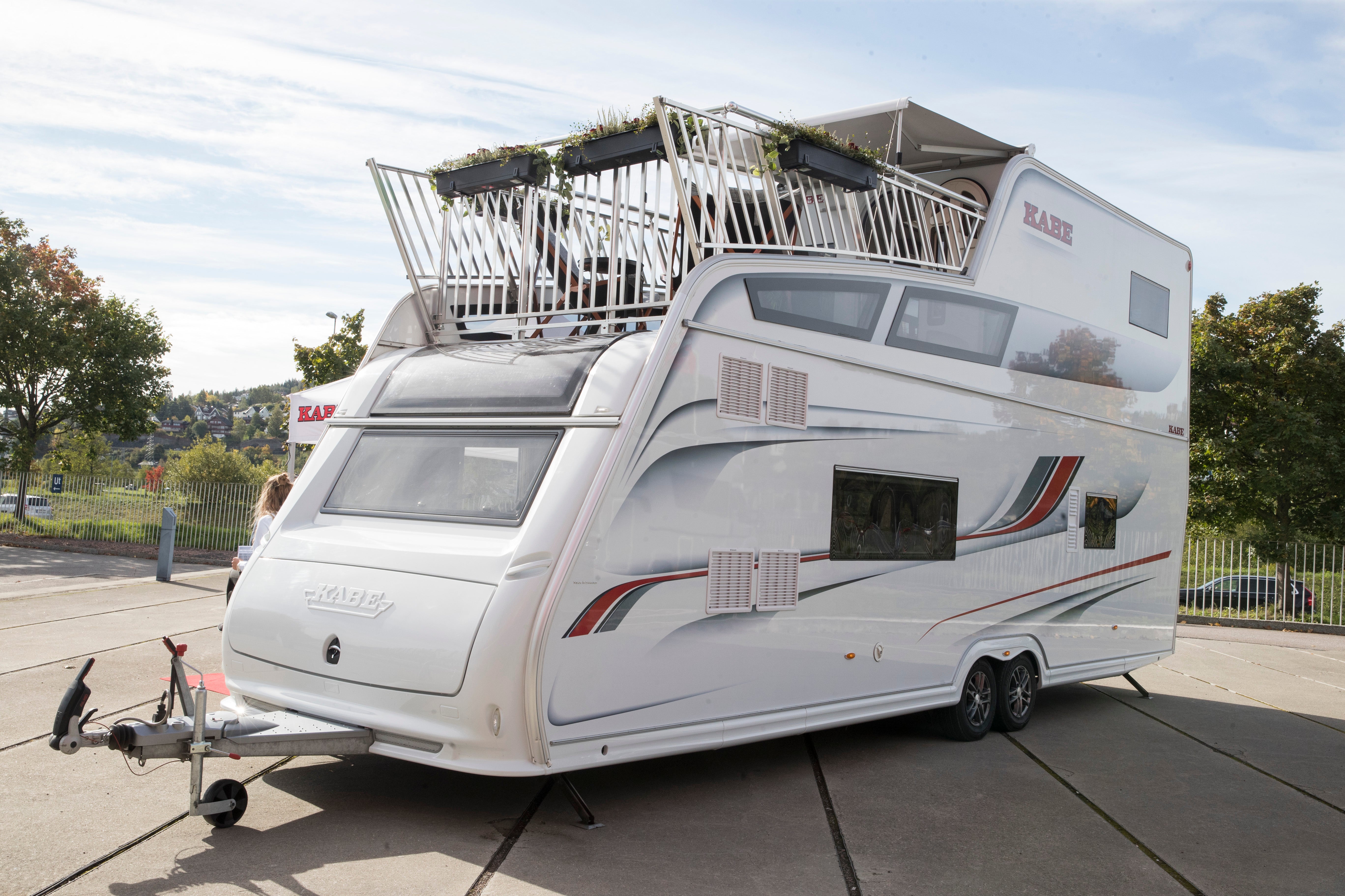En vit husbil med utökat takräcke parkerad på en väg