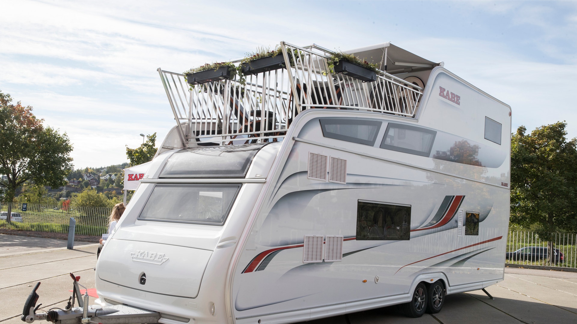 En vit husbil med utökat takräcke parkerad på en väg