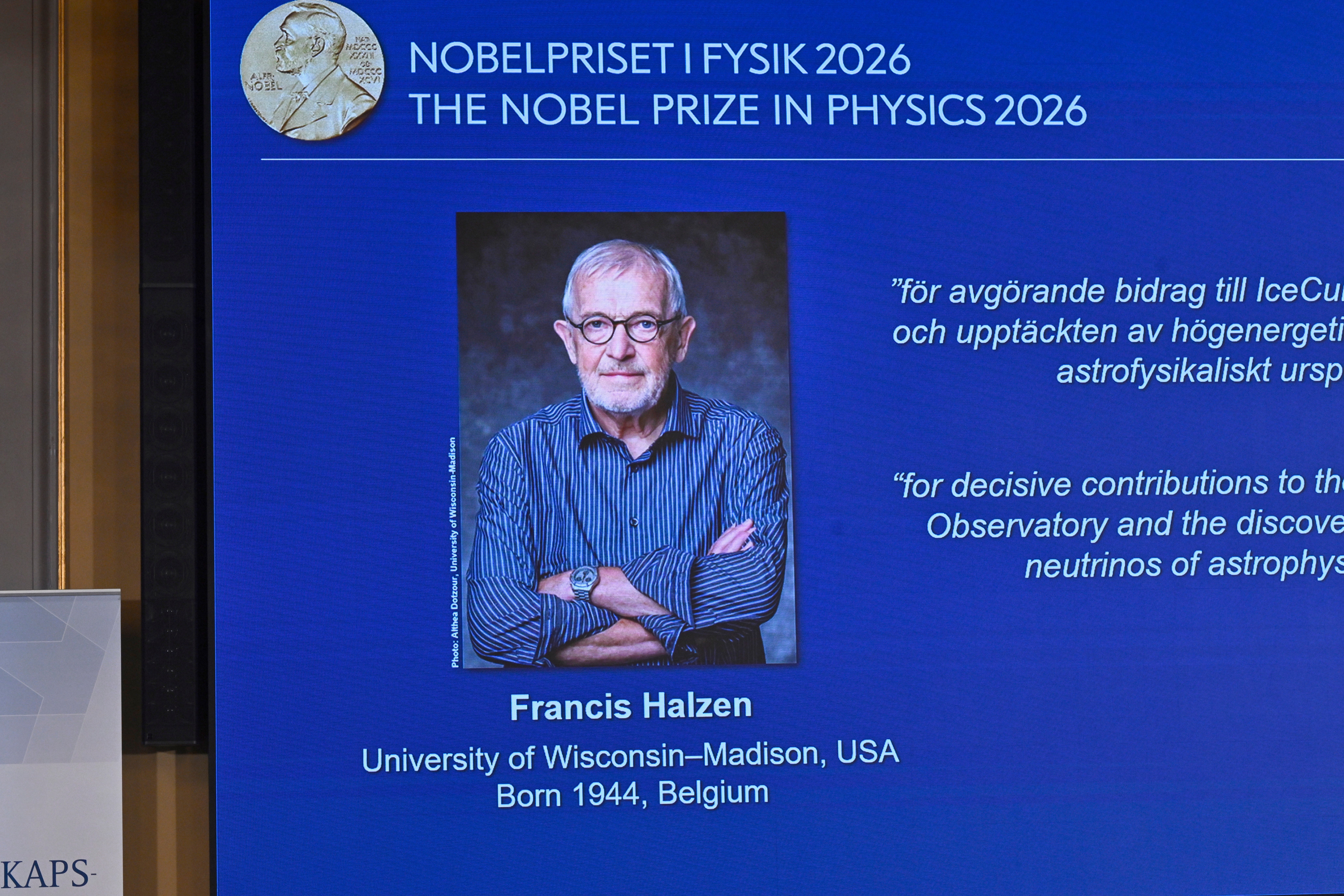 Skärm som visar Nobelpriset i fysik 2026 med ett porträtt av pristagaren Francis Halzen, en äldre man med glasögon och korslagda armar.