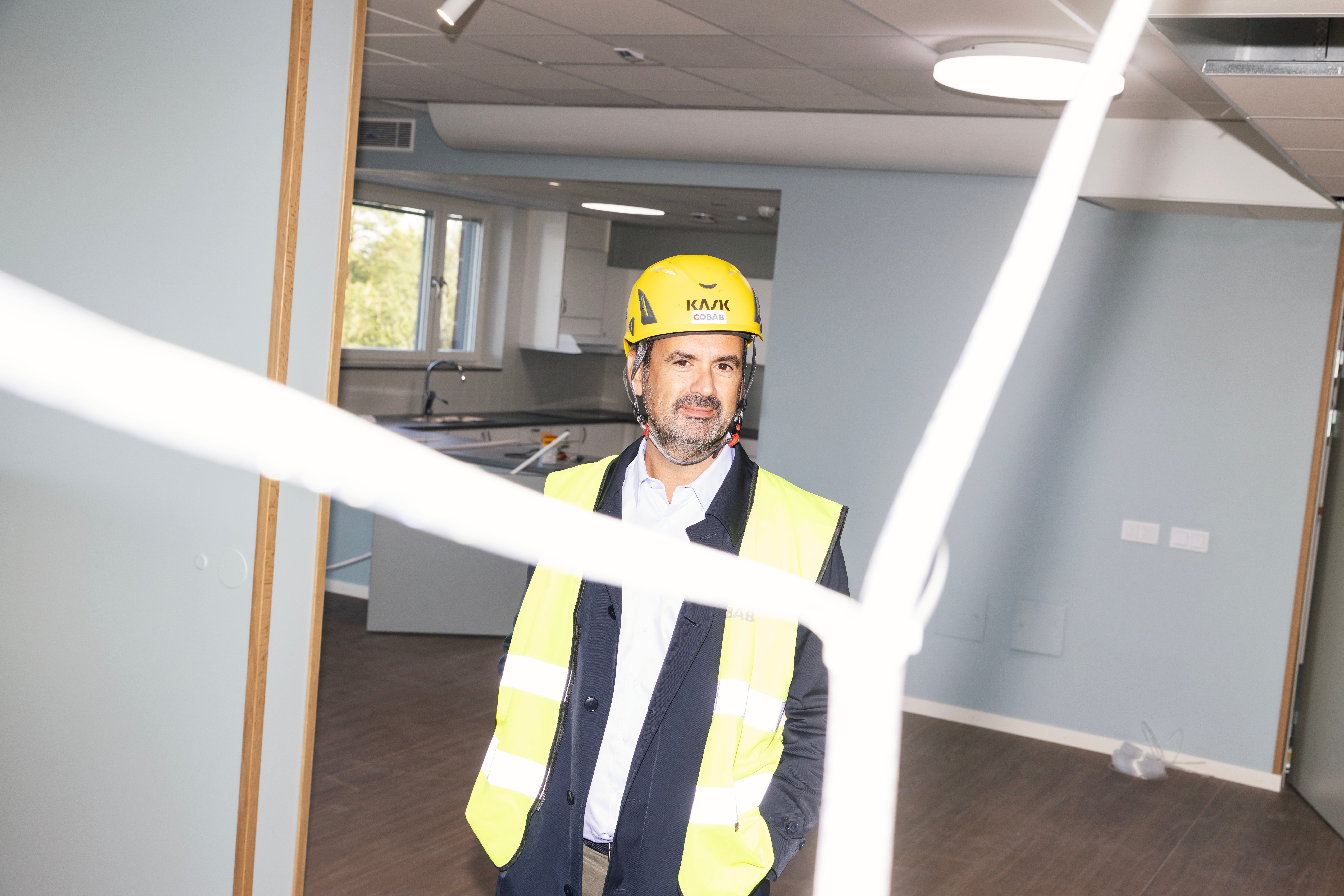 Man med hjälm och reflexväst står i ett ofärdigt rum under renovering.