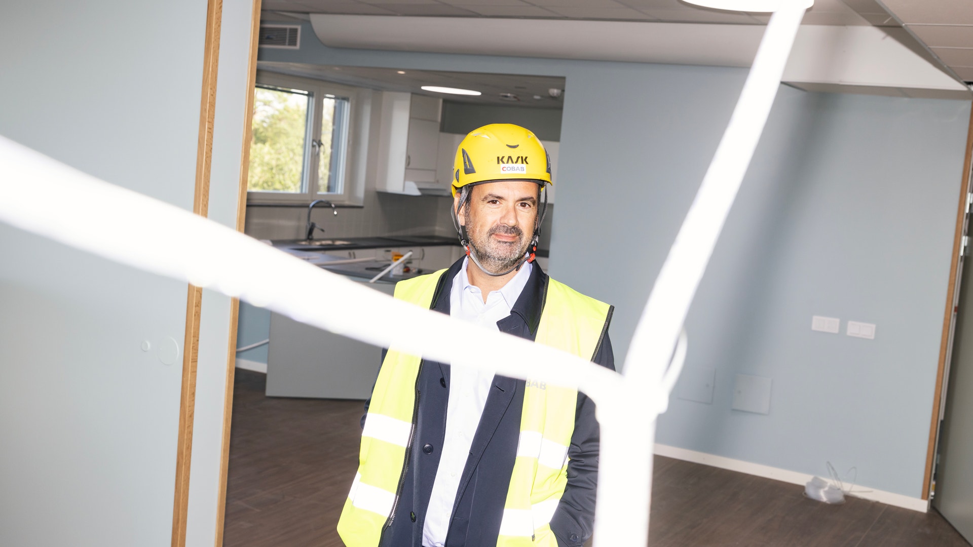 Man med hjälm och reflexväst står i ett ofärdigt rum under renovering.