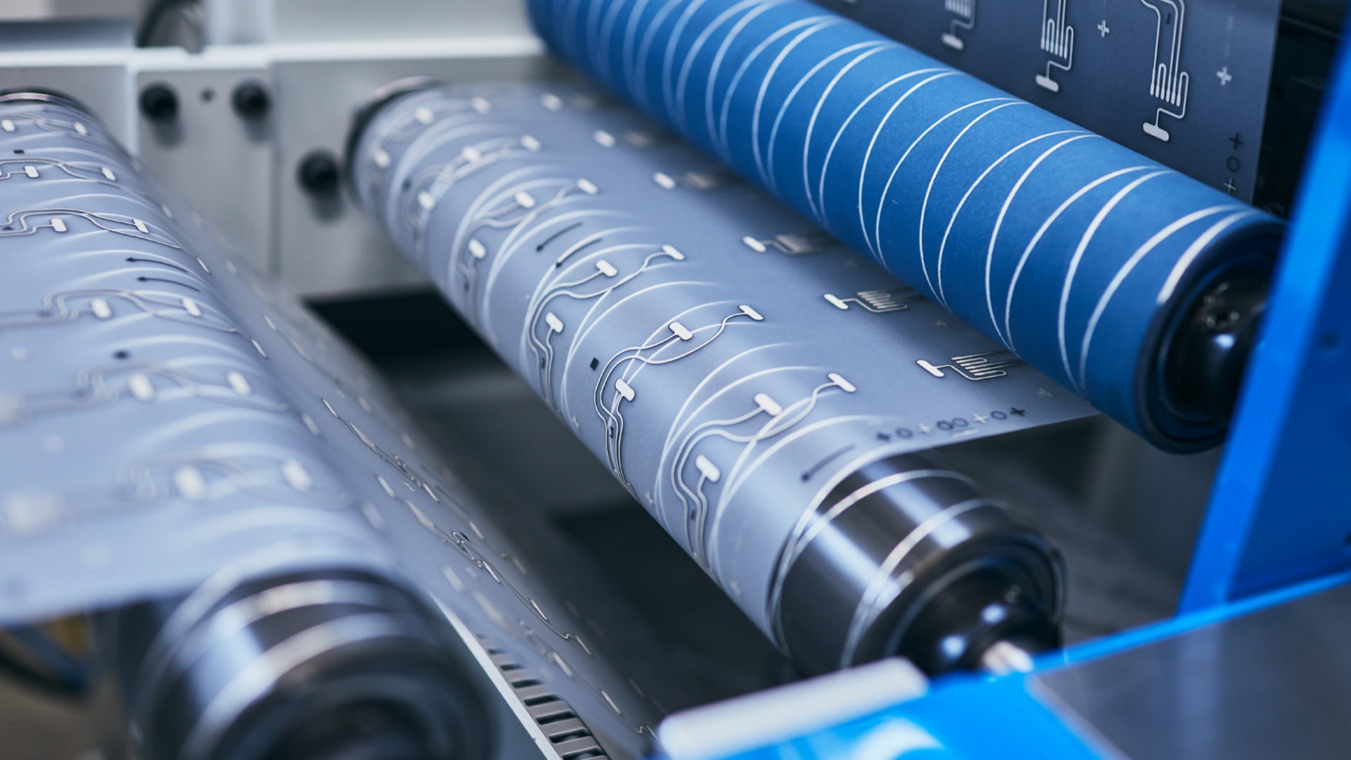 Närbild av industriella tryckvalsar med blå detaljer och kontrollpanel