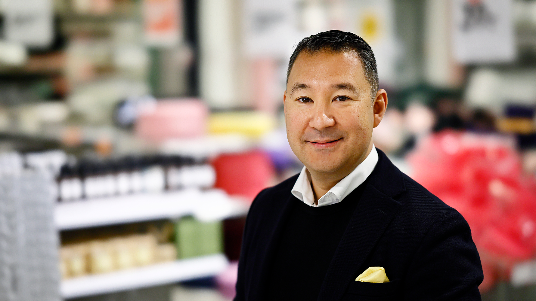 Porträtt av en man i svart tröja mot en suddig bakgrund av ett kontor eller arbetsplats.