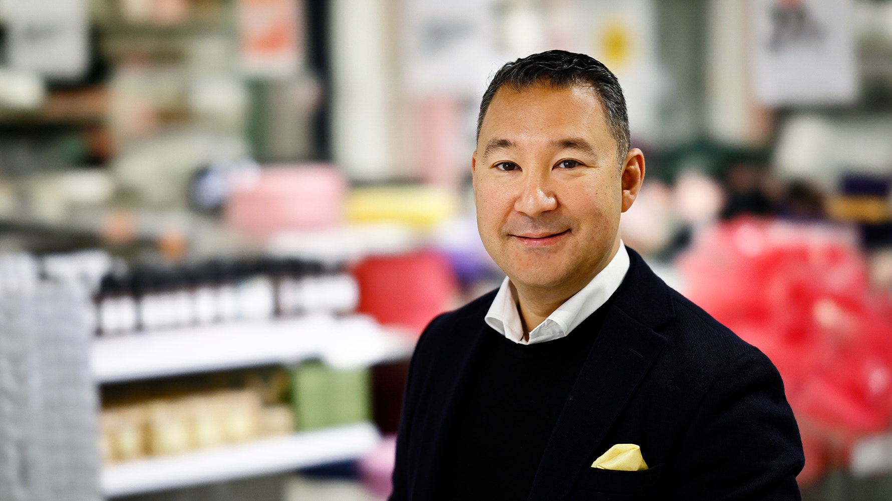 Porträtt av en man i svart tröja mot en suddig bakgrund av ett kontor eller arbetsplats.