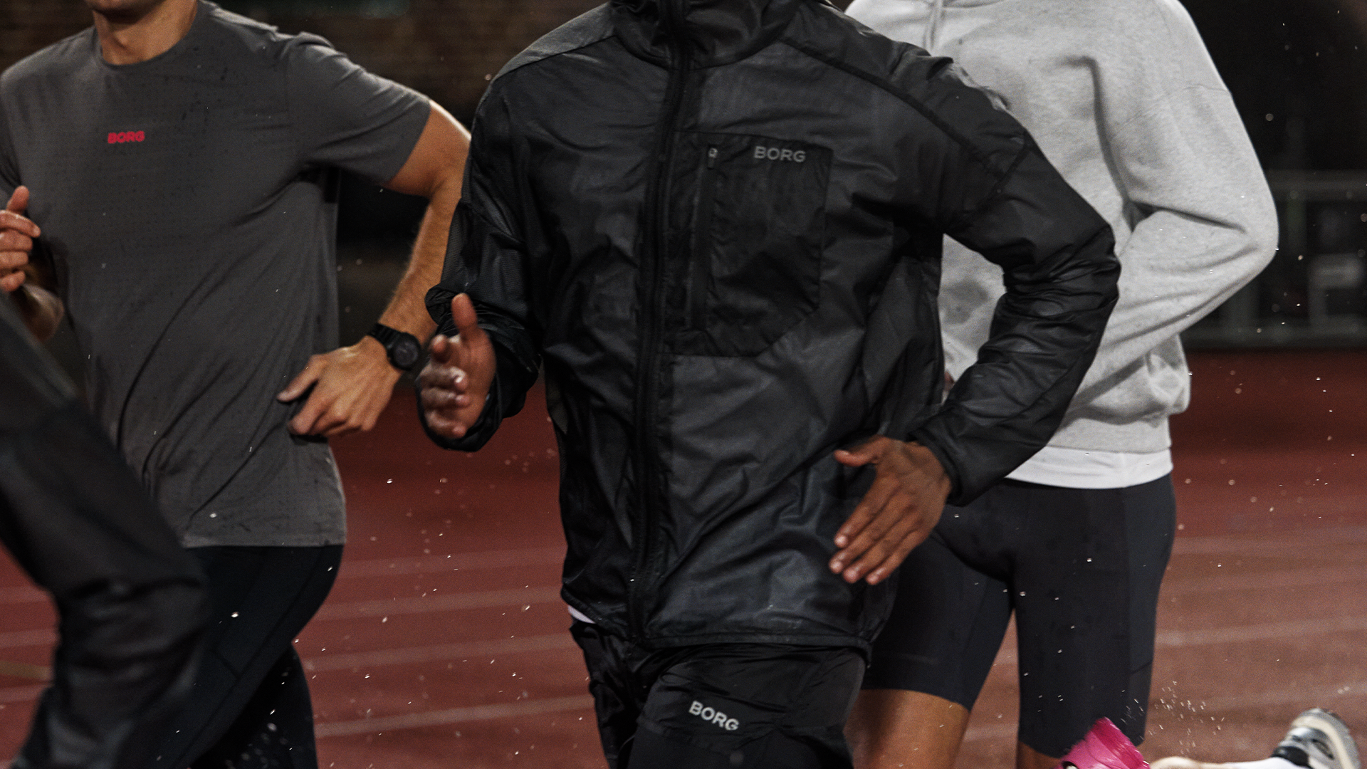 Tre personer springer tillsammans utomhus i sportkläder.