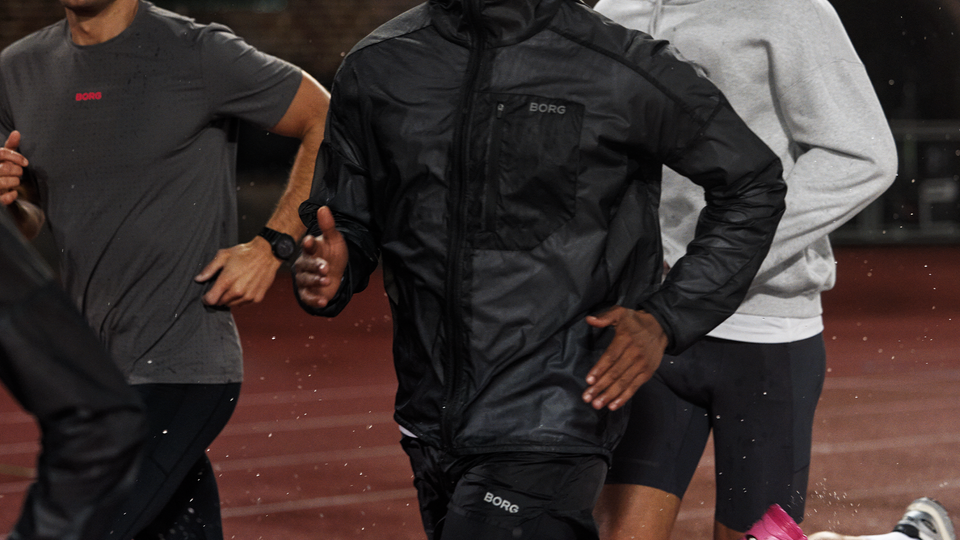 Tre personer springer tillsammans utomhus i sportkläder.