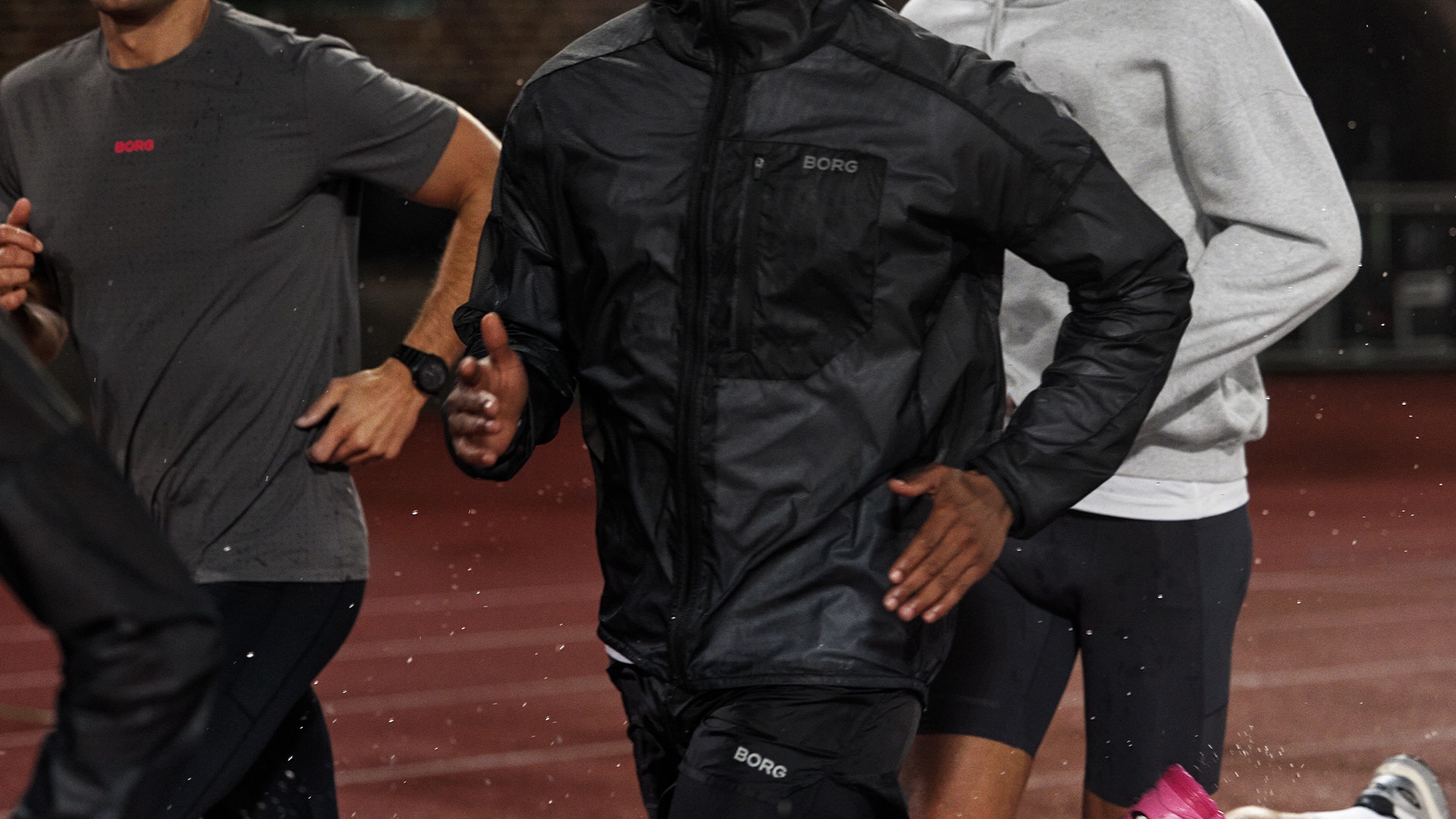 Tre personer springer tillsammans utomhus i sportkläder.