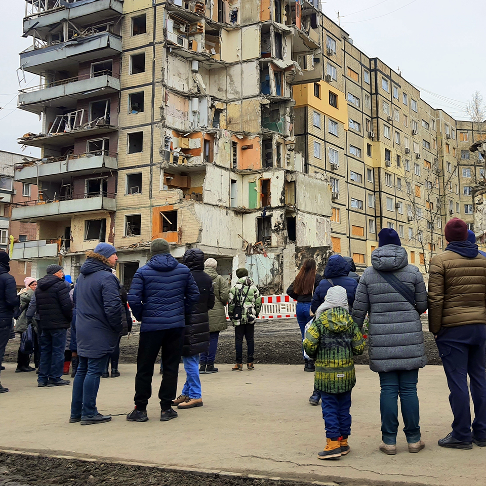 Människor samlade framför skadade bostadshus