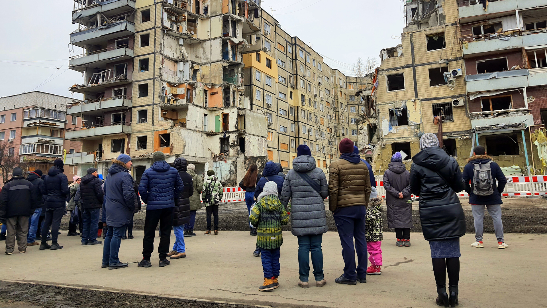 Människor samlade framför skadade bostadshus