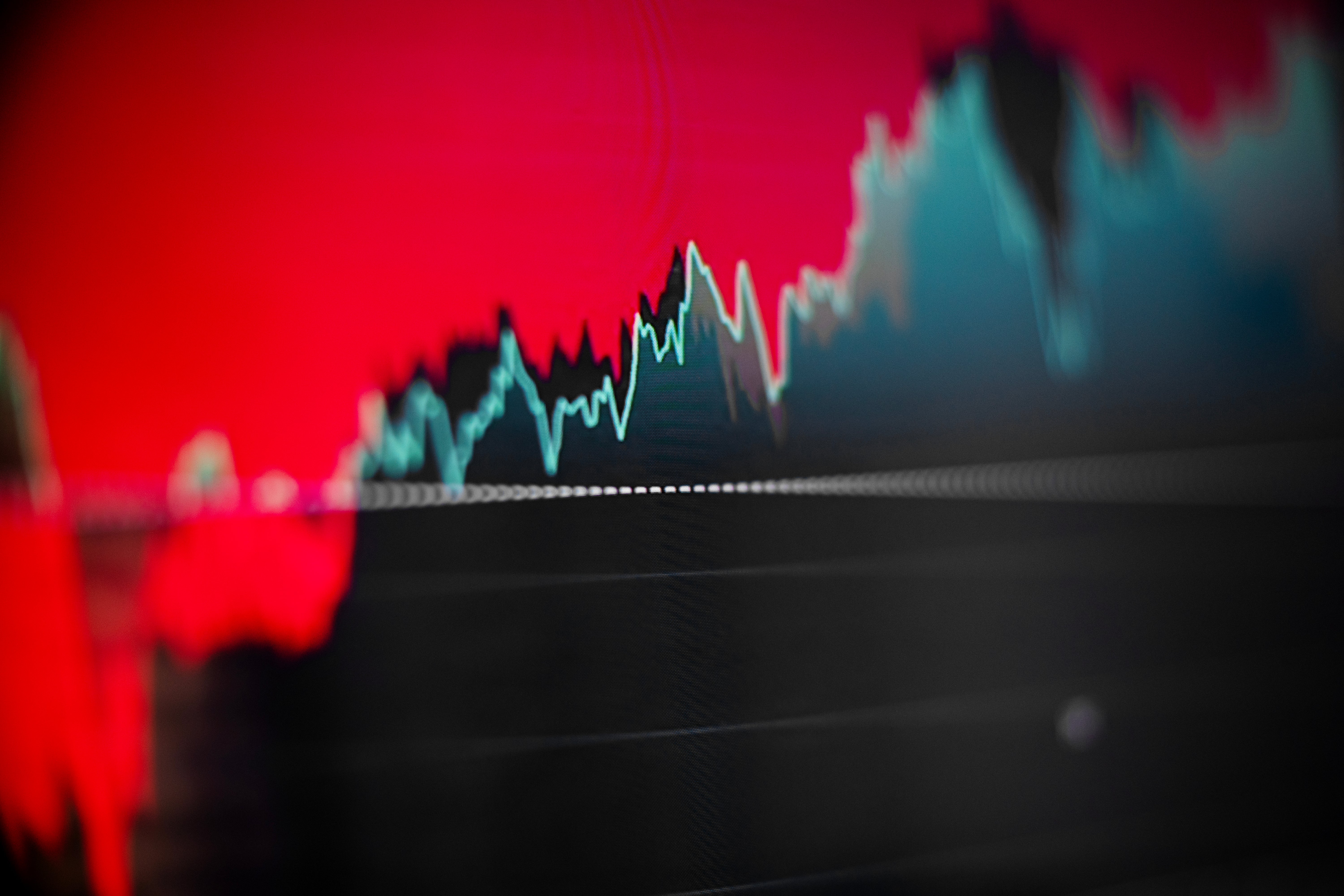 Finansiell graf som visar en stigande aktiekurs med en blågrön trendlinje mot en röd bakgrund.