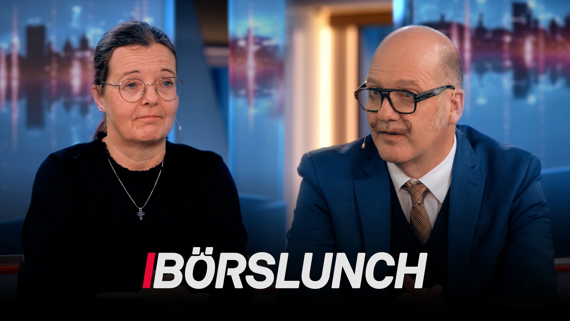 Två personer i en TV-studiosättning diskuterar börsnyheter