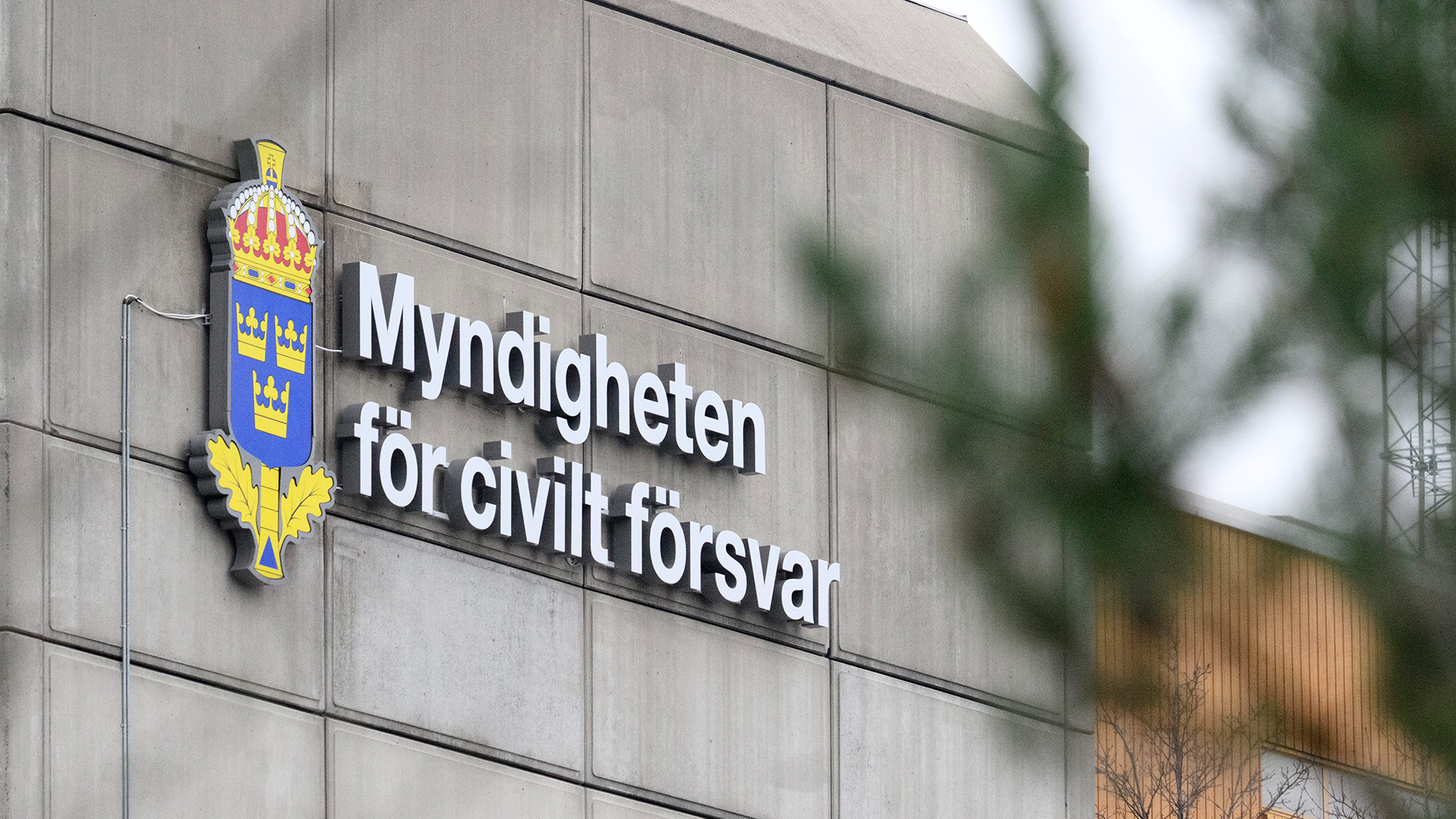 Skylt på byggnadsfasad med texten "Myndigheten för civilt försvar" och Sveriges riksvapen, en emblem med gul och blå färg