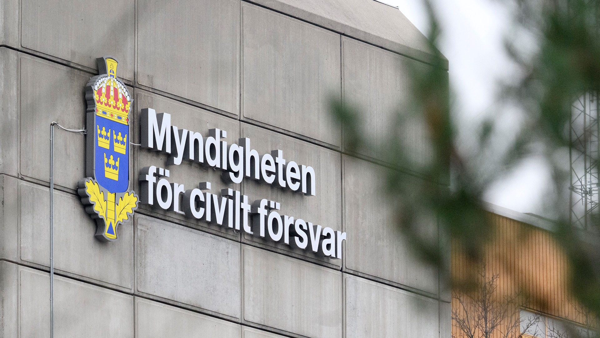 Skylt på byggnadsfasad med texten "Myndigheten för civilt försvar" och Sveriges riksvapen, en emblem med gul och blå färg