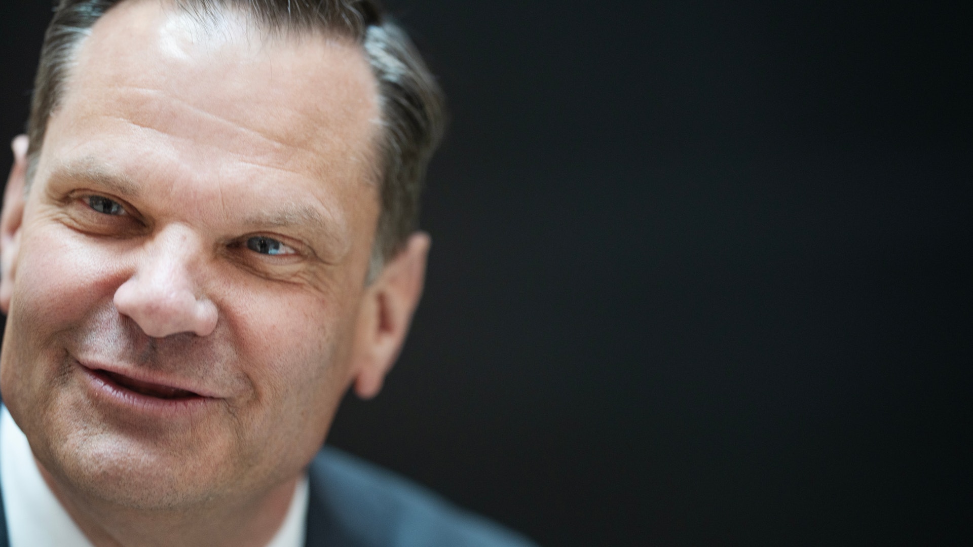 Porträtt av en man i kostym mot mörk bakgrund