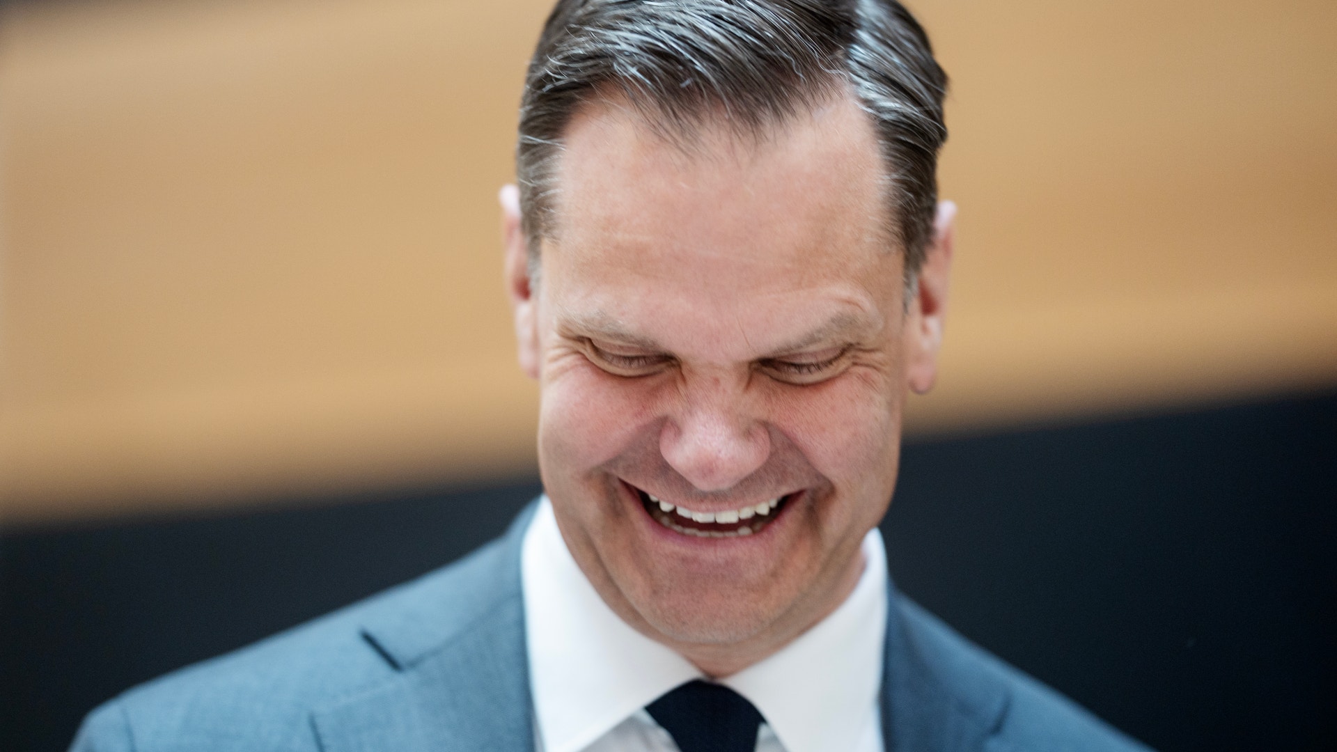 Porträtt av en man i kostym och slips som ler mot kameran.