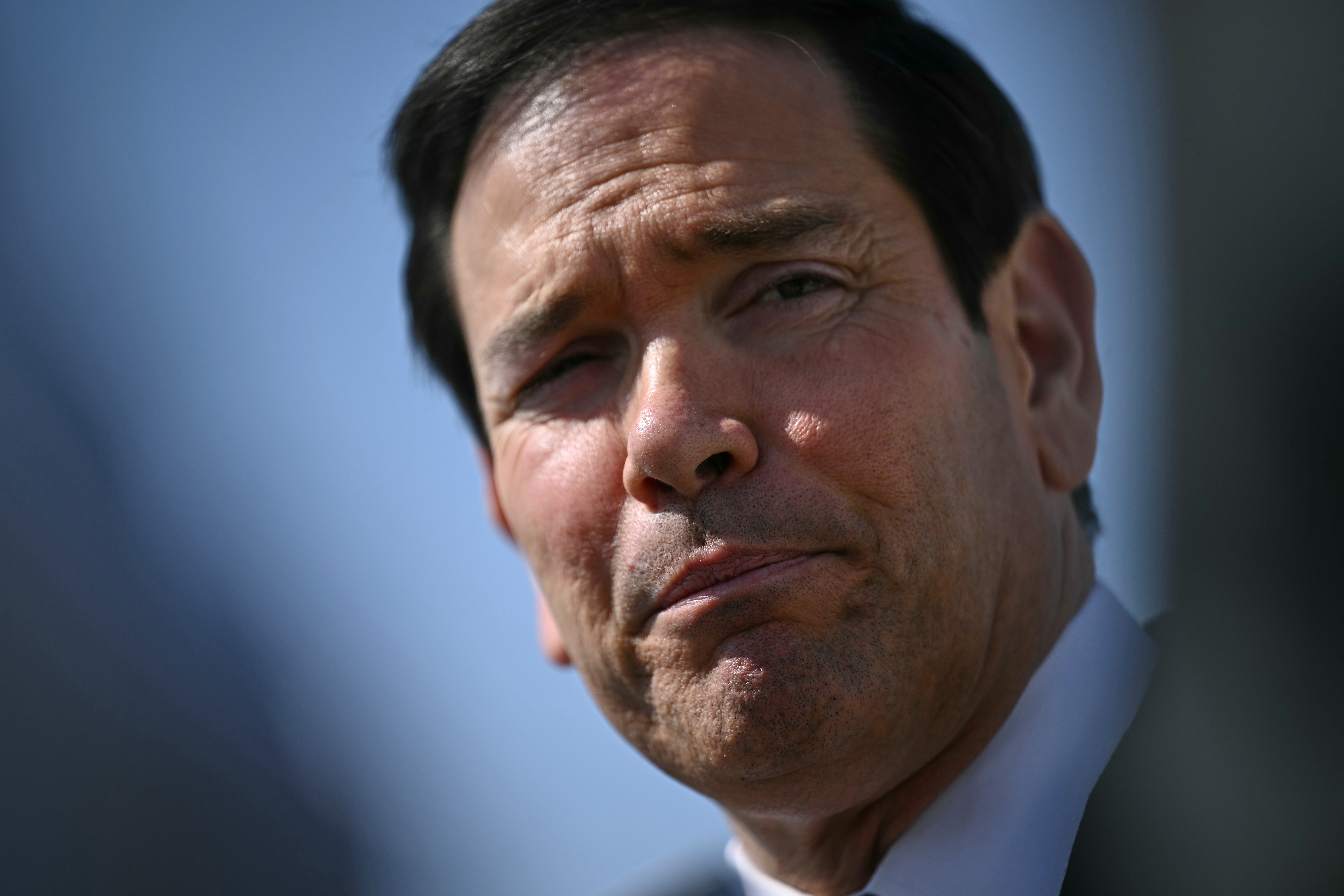 Porträtt av en man i vit skjorta mot blå bakgrund.