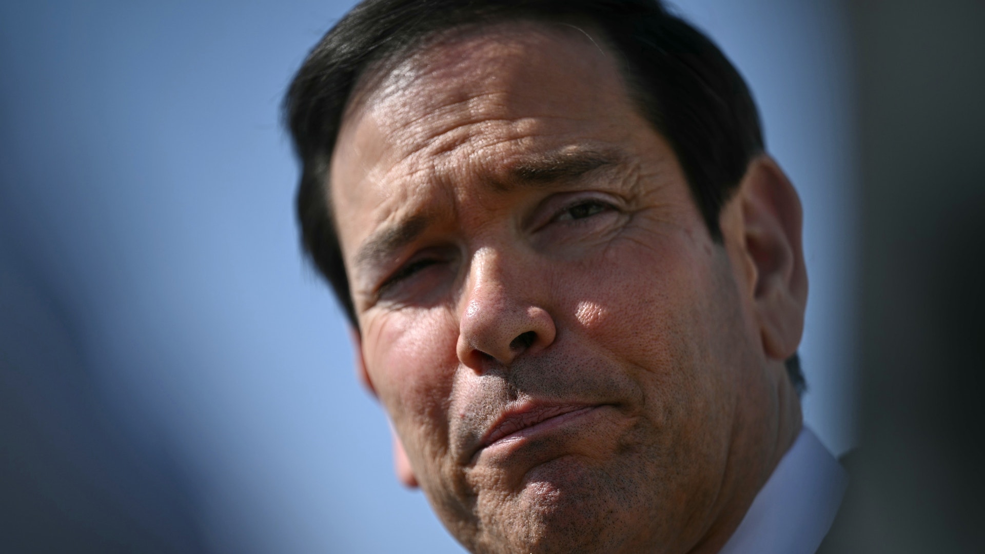 Porträtt av en man i vit skjorta mot blå bakgrund.