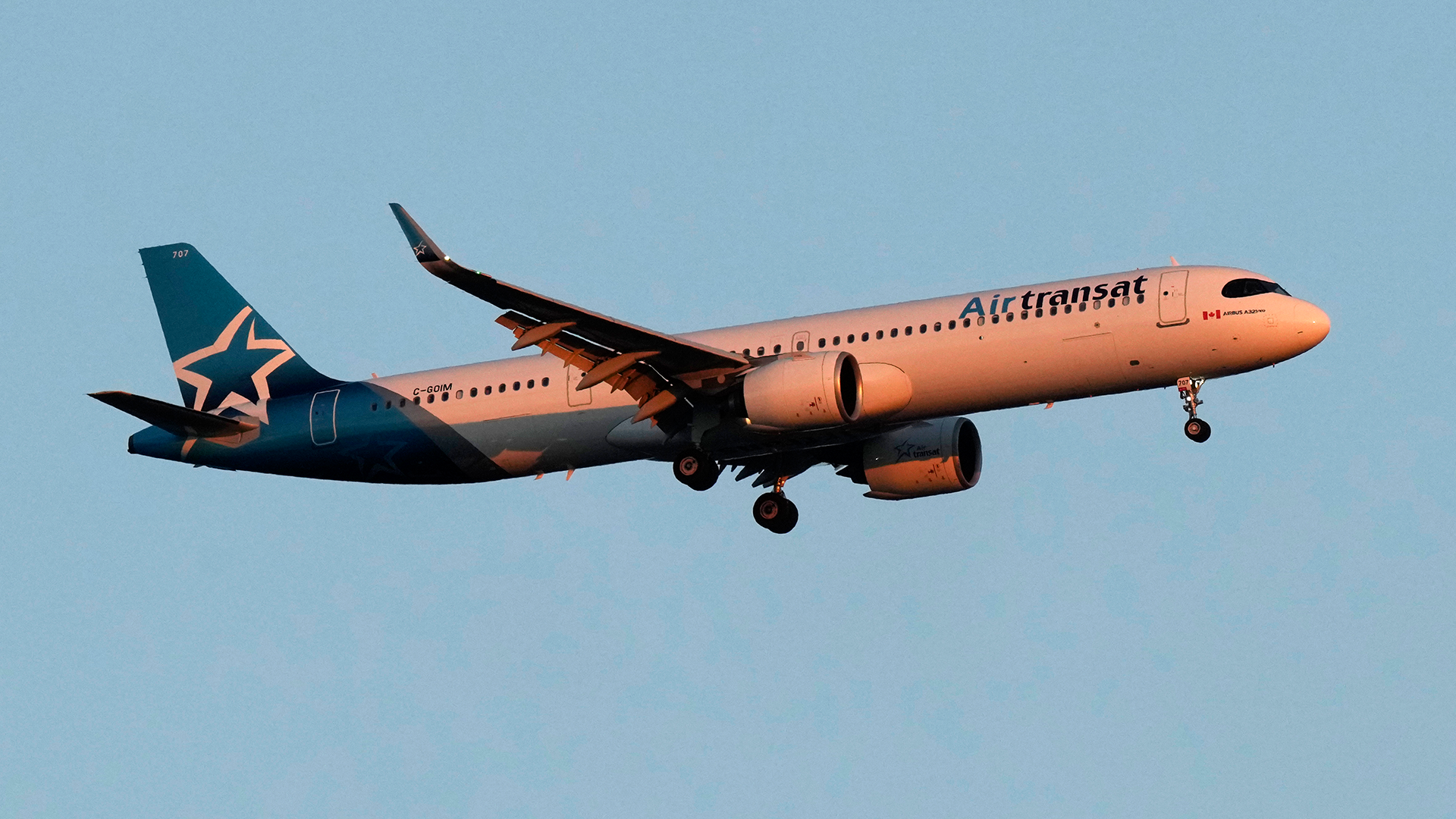 Ett passagerarflygplan från Air Transat flyger mot en klarblå himmel.