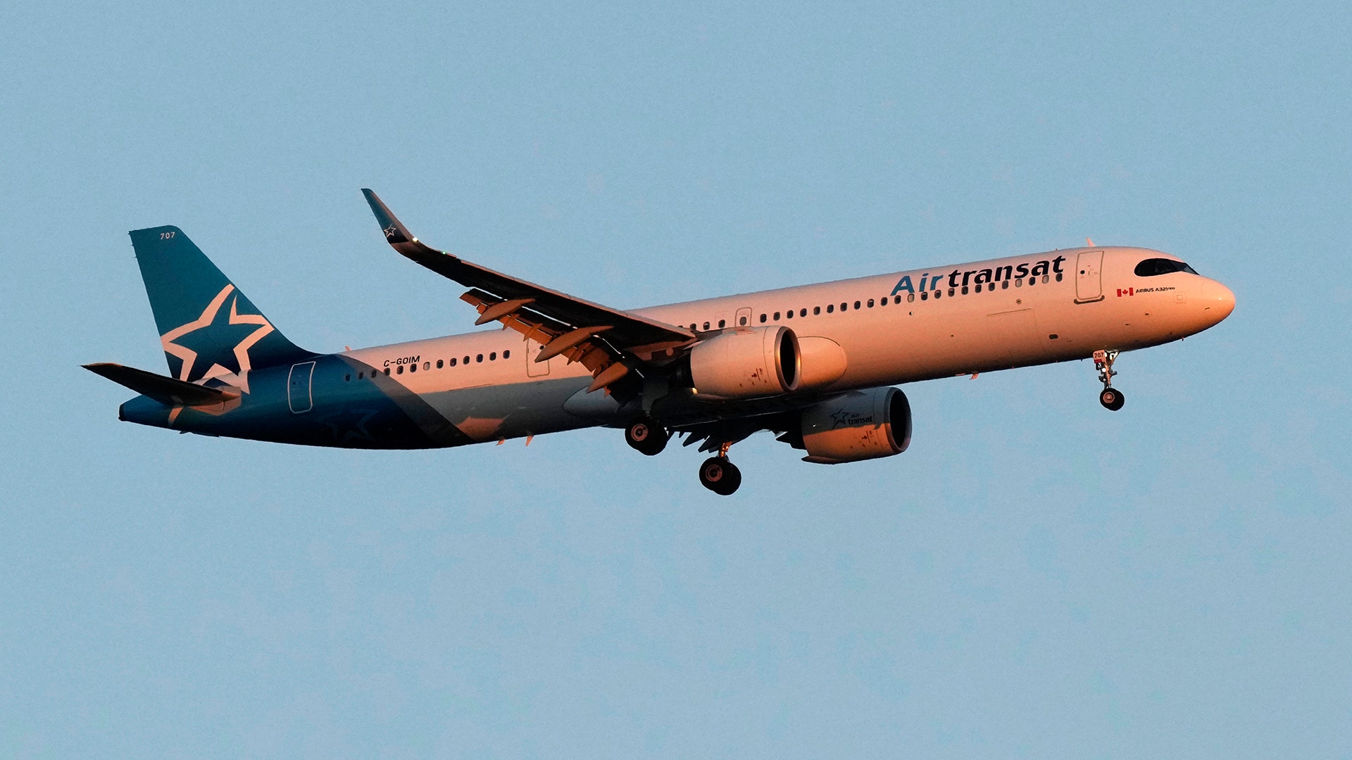 Ett passagerarflygplan från Air Transat flyger mot en klarblå himmel.