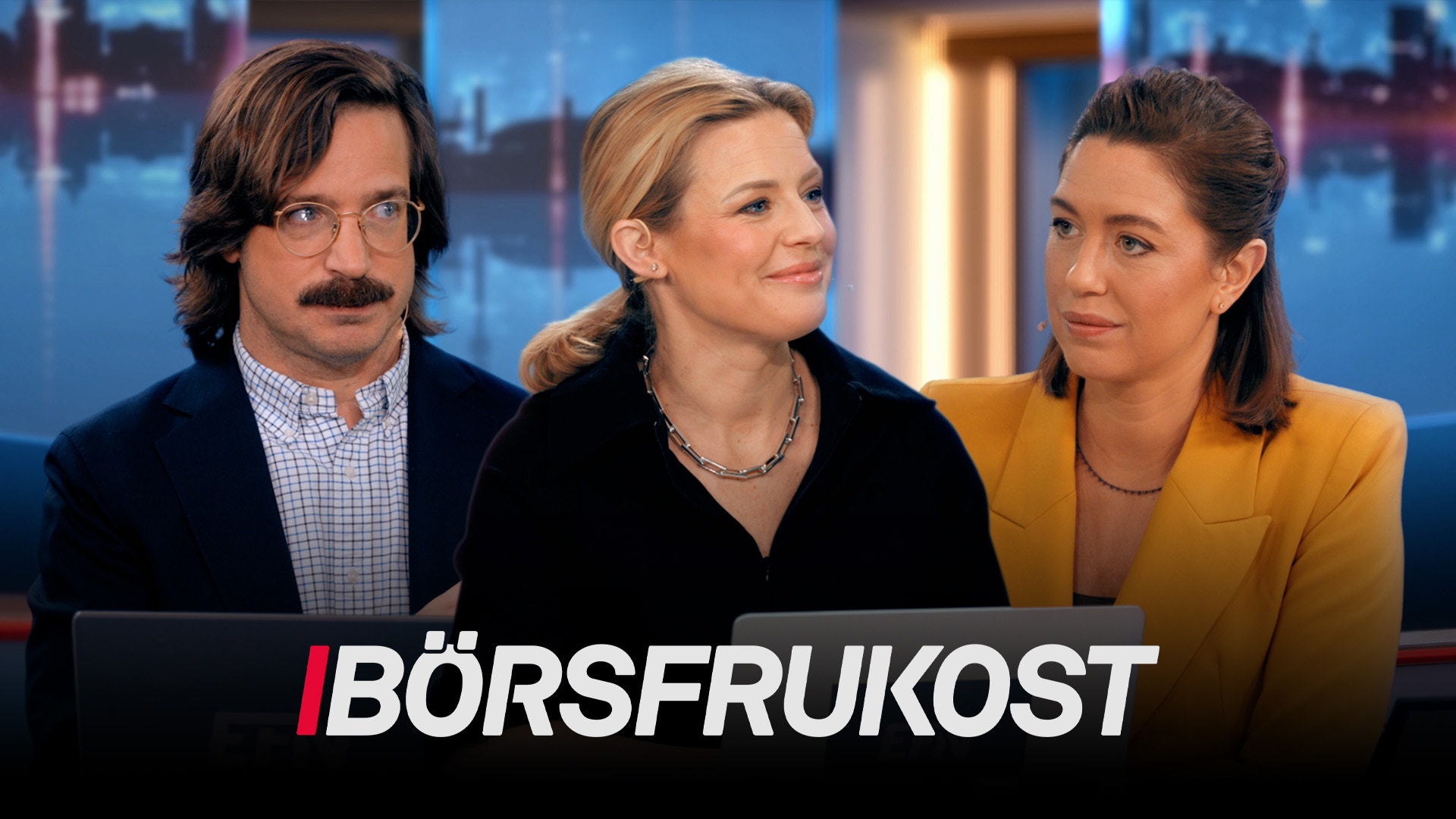 Tre personer i en TV-studio med stadsvy i bakgrunden under programmet Börsfrukost.
