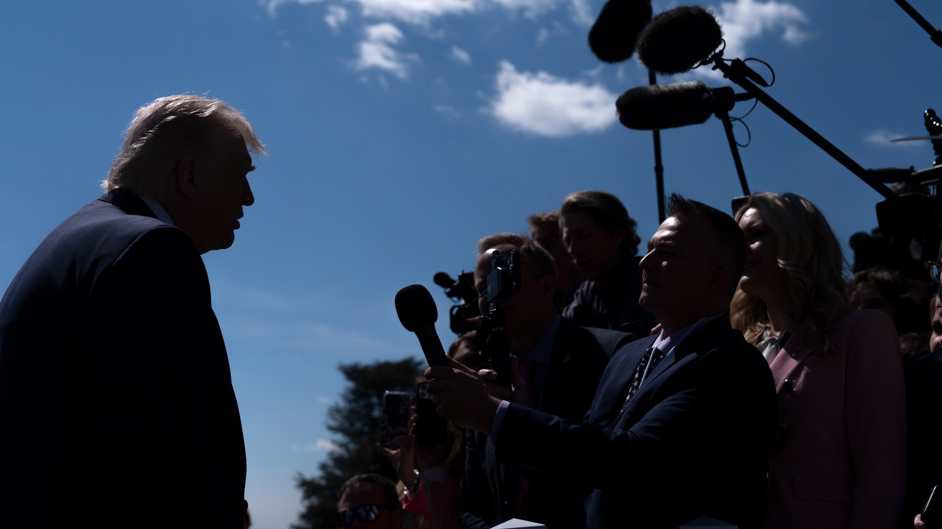 Man intervjuas av journalister och mediafolk med kameror och mikrofoner utomhus