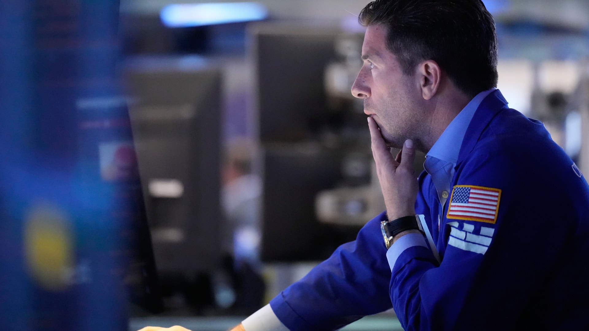 Man i blå uniform tittar på en datorskärm i ett belyst kontrollrum.