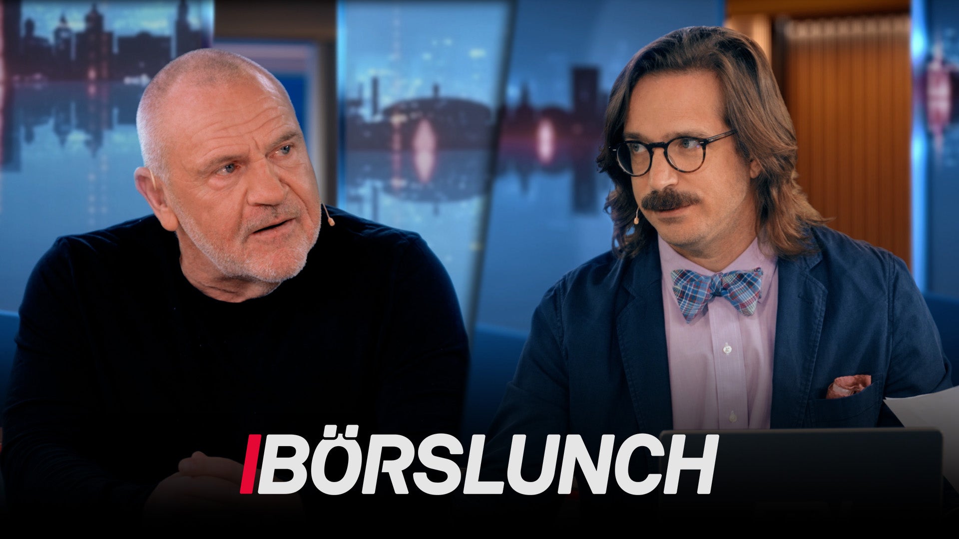 Två män i en TV-studio med stadshorisont i bakgrunden. Logotypen BÖRSLUNCH syns längst ned på skärmen.