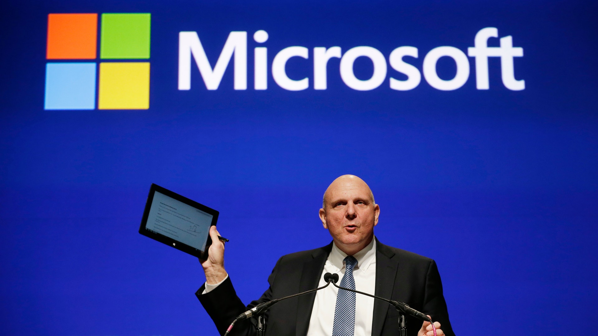 Steve Ballmer som håller i en surfplatta framför en Microsoft-logga