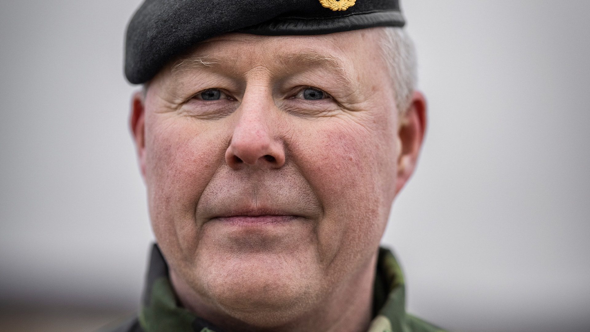 Porträtt av en man i militär uniform med svart baskermössa