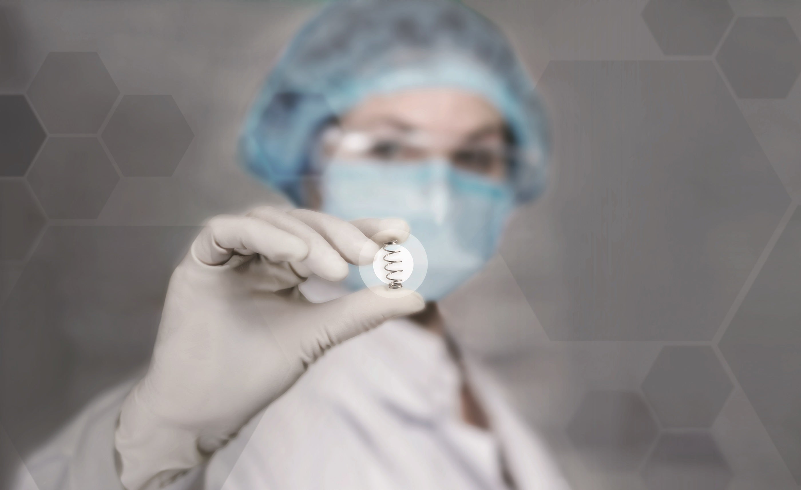 Sjukvårdspersonal i skyddsutrustning håller upp ett litet föremål.