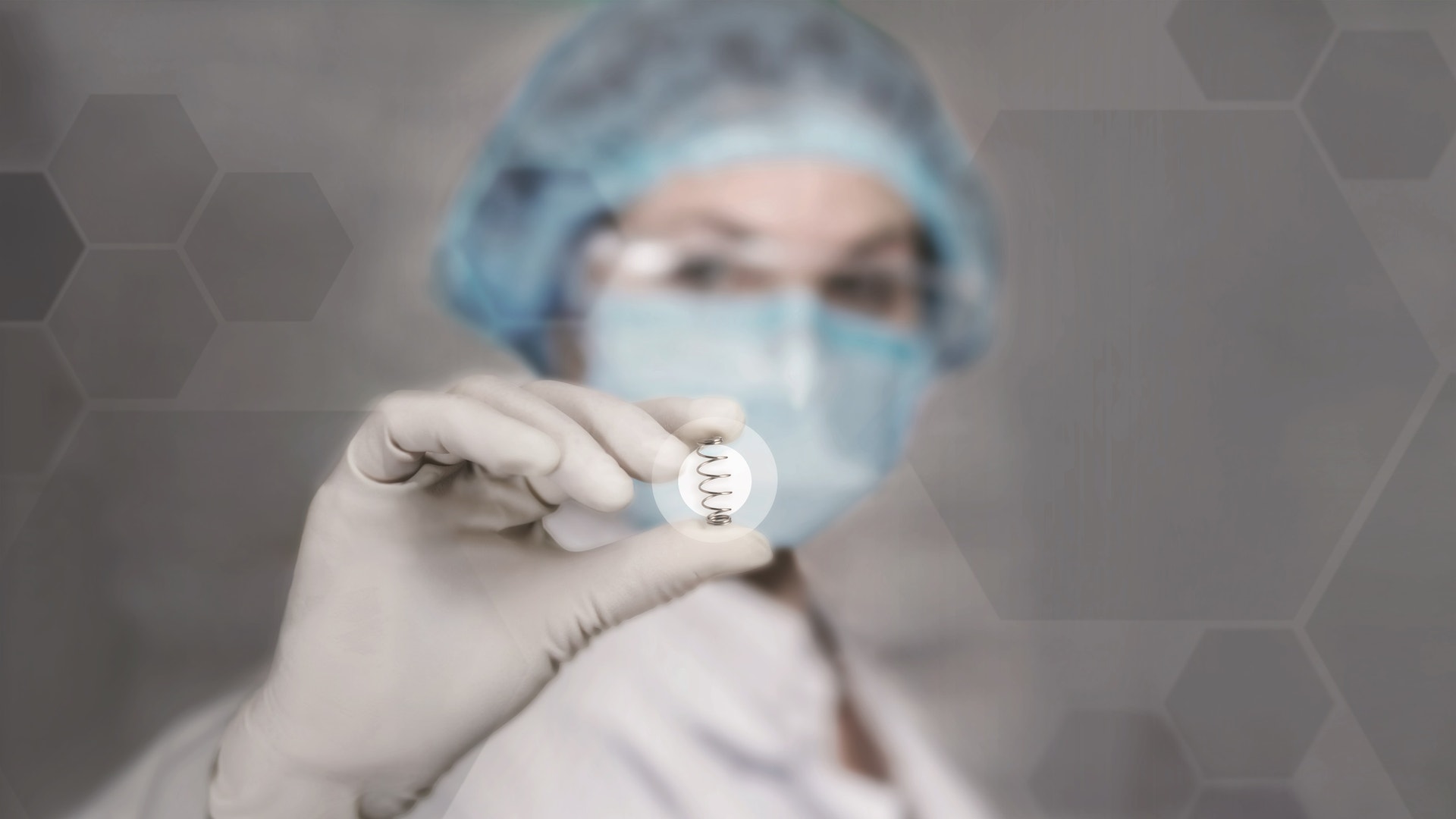 Sjukvårdspersonal i skyddsutrustning håller upp ett litet föremål.