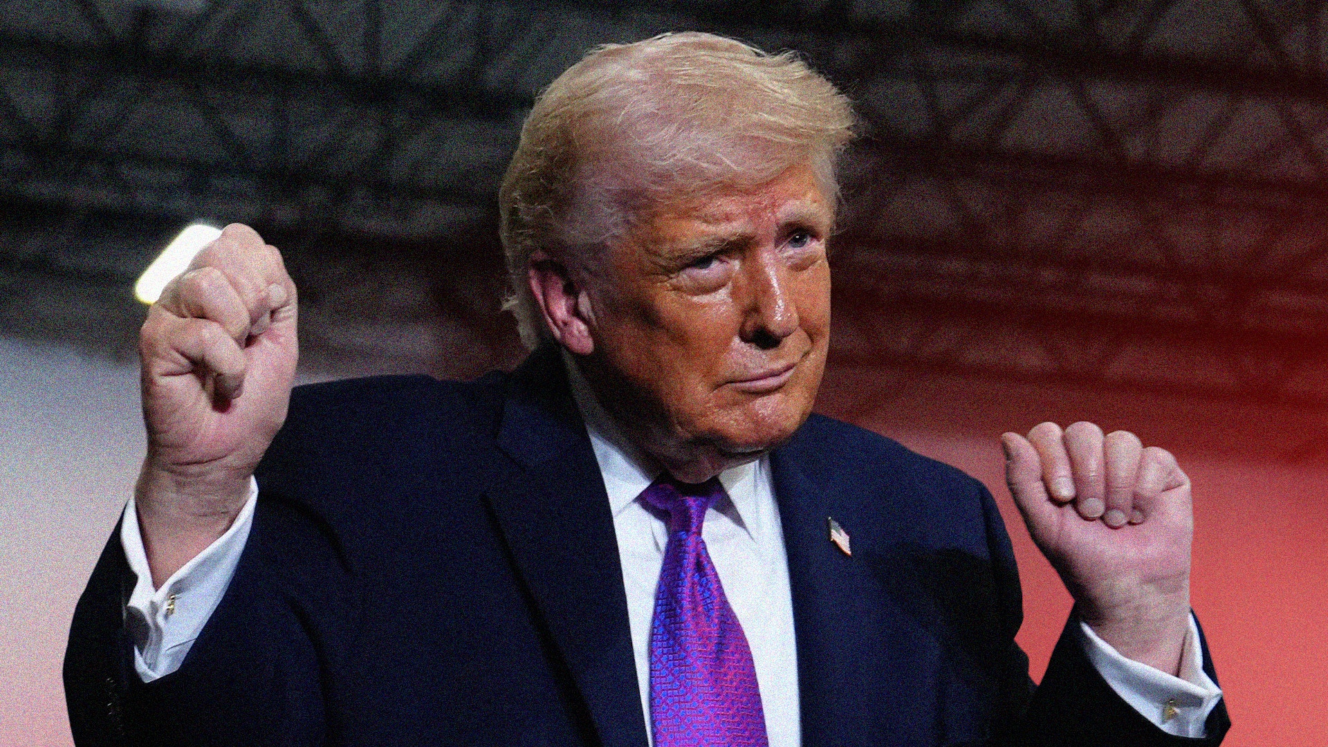 Man i mörk kostym och lila slips med båda närvarna upphöjda i en triumfande gest