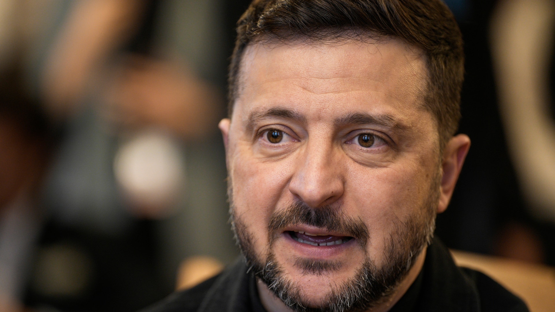 Porträtt av en man med skägg, iklädd mörk klädsel.