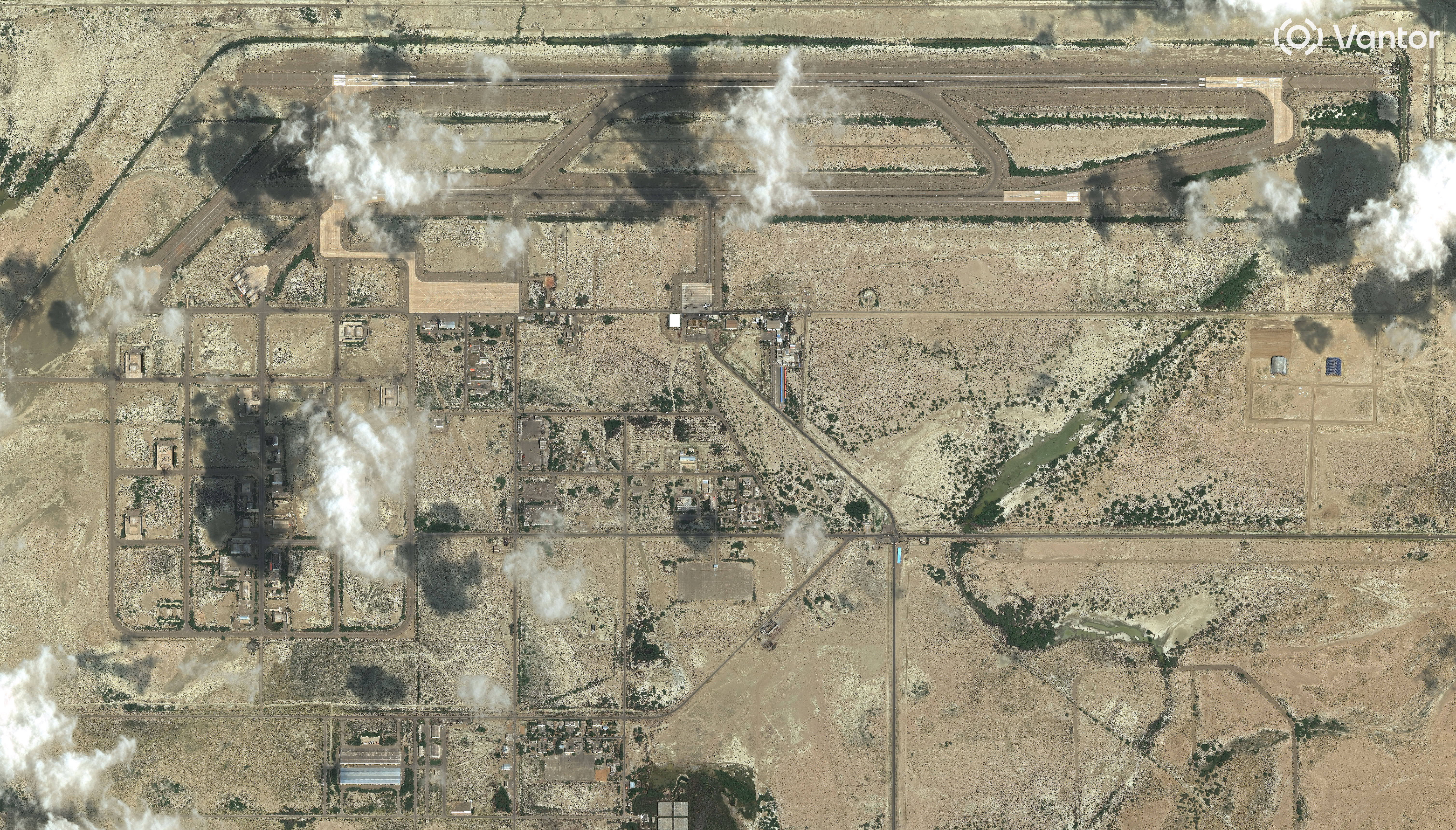Flygfoto över industrianläggning i ökenlandskap med rökmoln som stiger från fabriksbyggnader